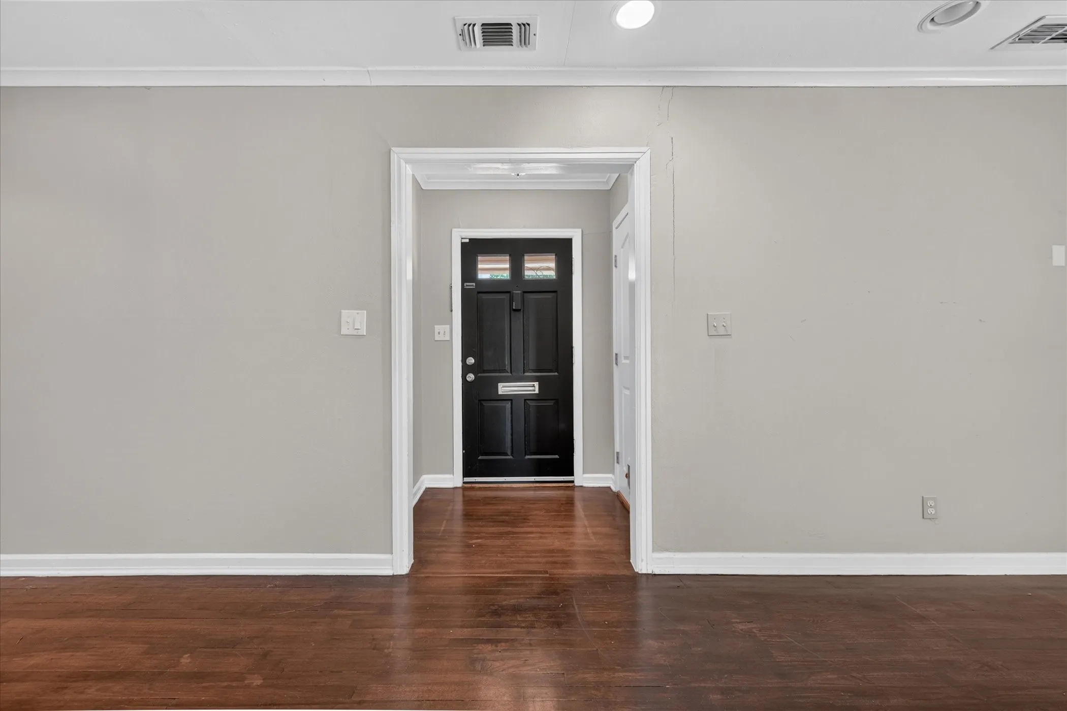 Wood-finish flooring with light gray walls, white crown molding, and recessed lighting