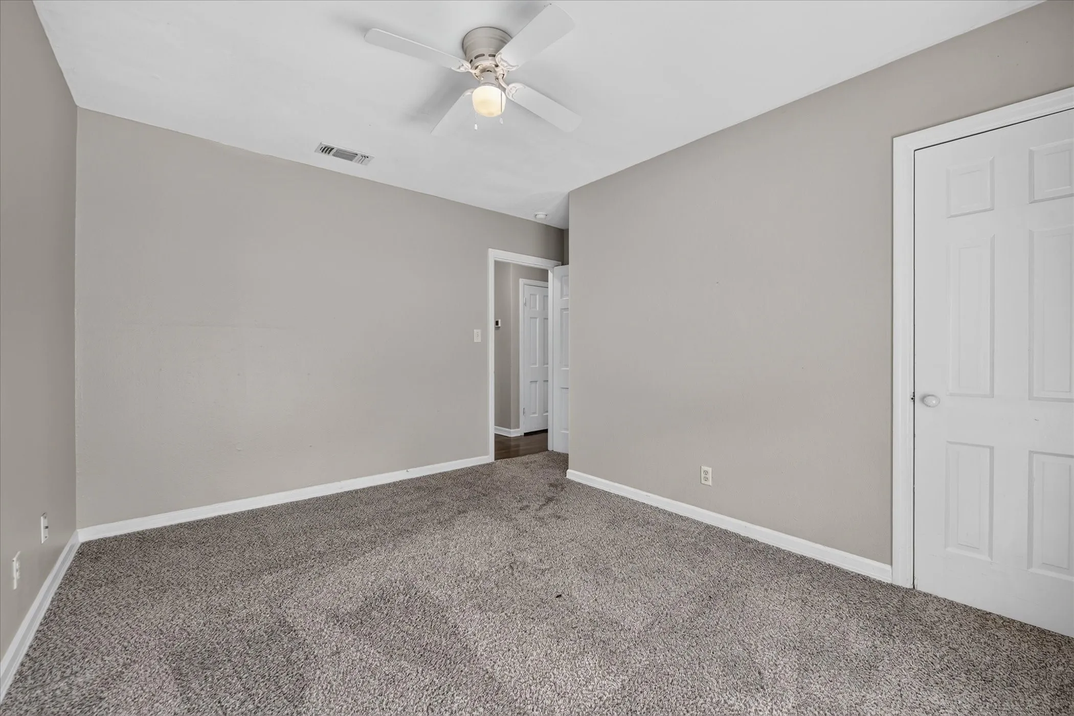 Plush carpet flooring, light neutral wall paint, white interior doors, and a ceiling fan with integrated lighting
