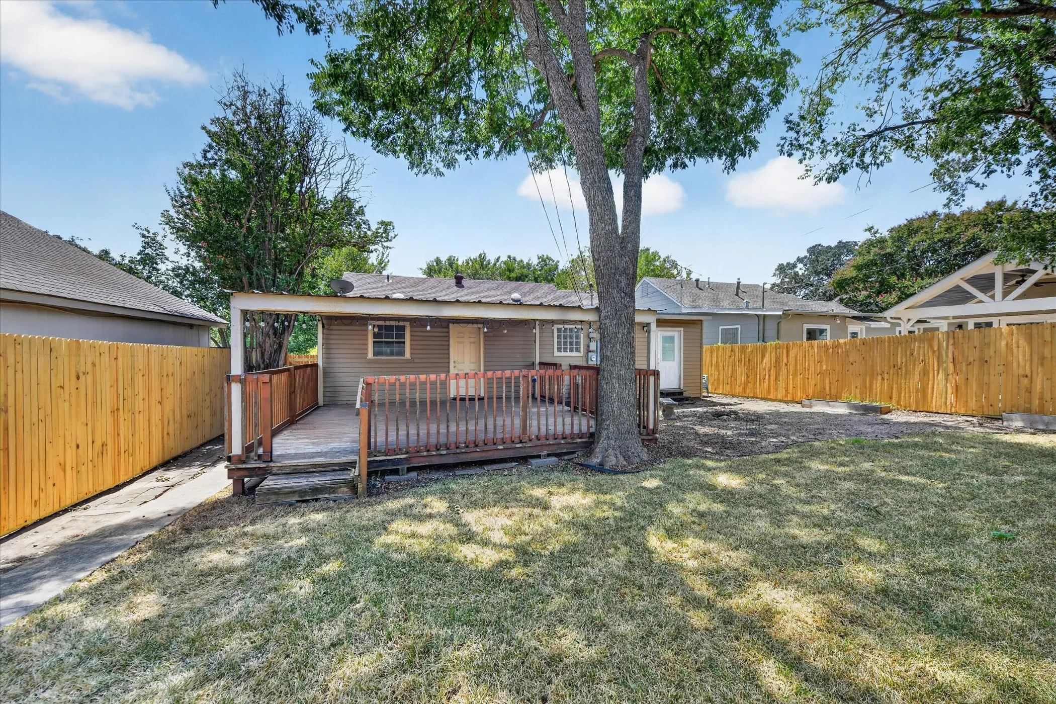 Expansive backyard featuring a covered wood deck, wood privacy fencing, and mature trees