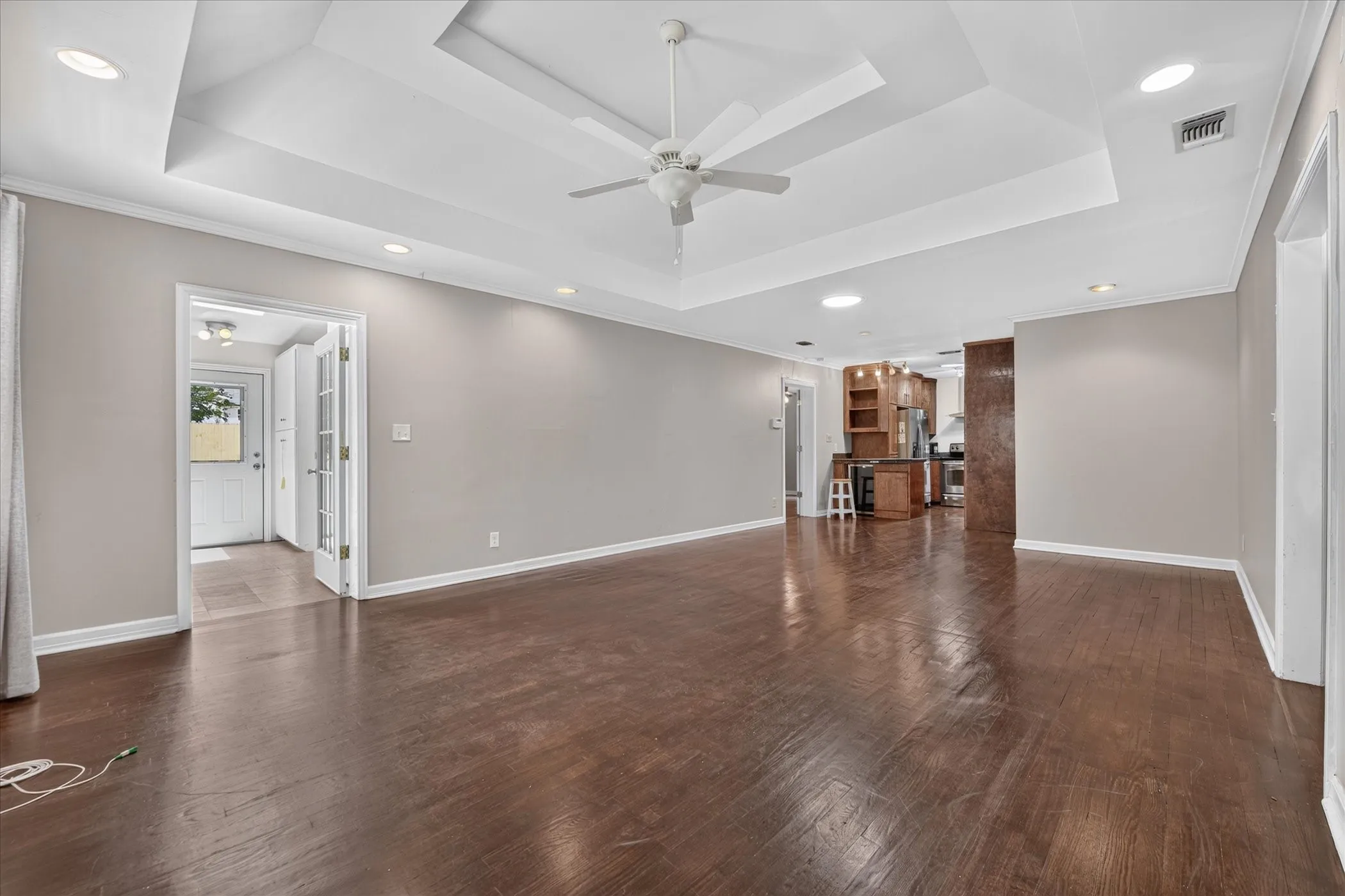 Wood-finish flooring, recessed lighting, ceiling fan, and tray ceiling