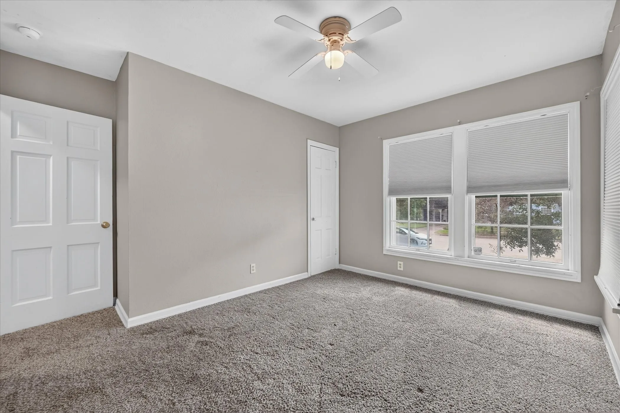 Neutral paint palette, ceiling fan with integrated lighting, two panel doors, and textured carpeting