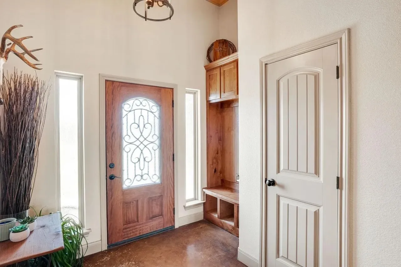 Wood-paneled entry door with decorative ironwork, flanked by vertical windows