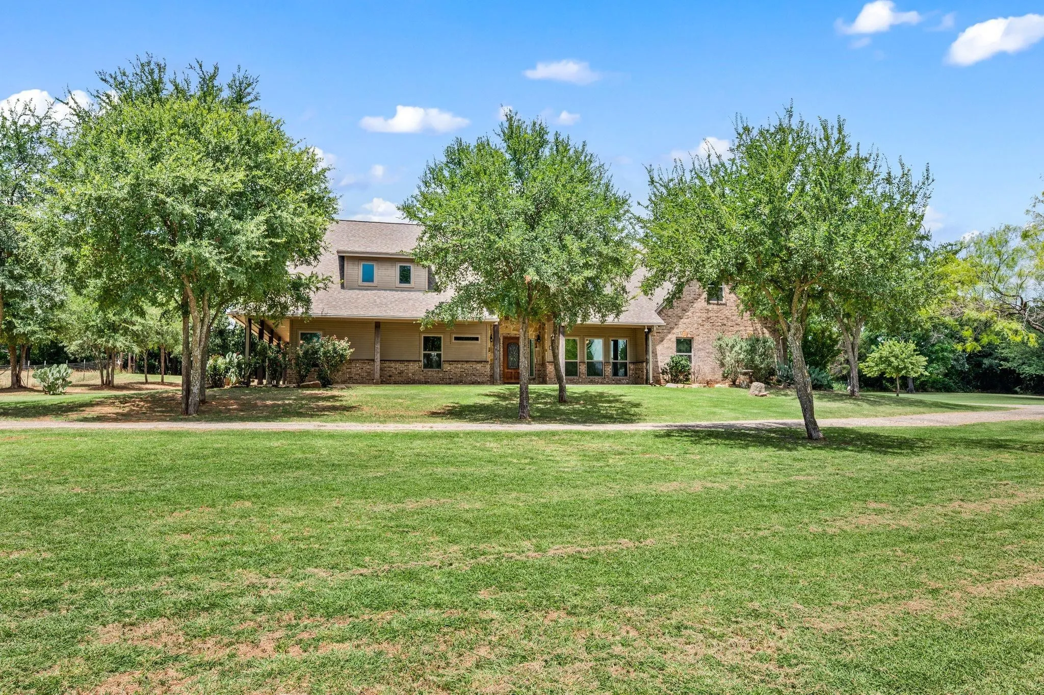 Brick and stucco exterior with multiple windows, covered front porch with columns, and dormer windows