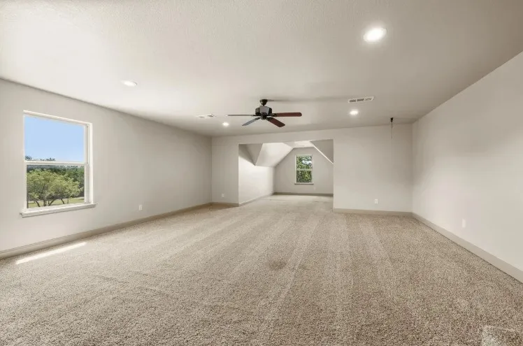 Spacious room featuring neutral carpet, recessed lighting, and a ceiling fan