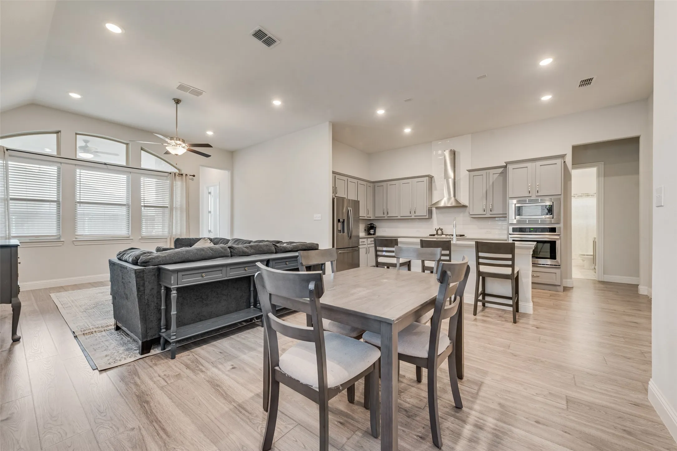 View into the dining room, living room and kitchen with engineered hardwood floors, shaker cabinets, quartz countertops, and 11 ft ceilings at 1721 Pattenson Trl, Haslet, TX 76052 in Wellington subdivision