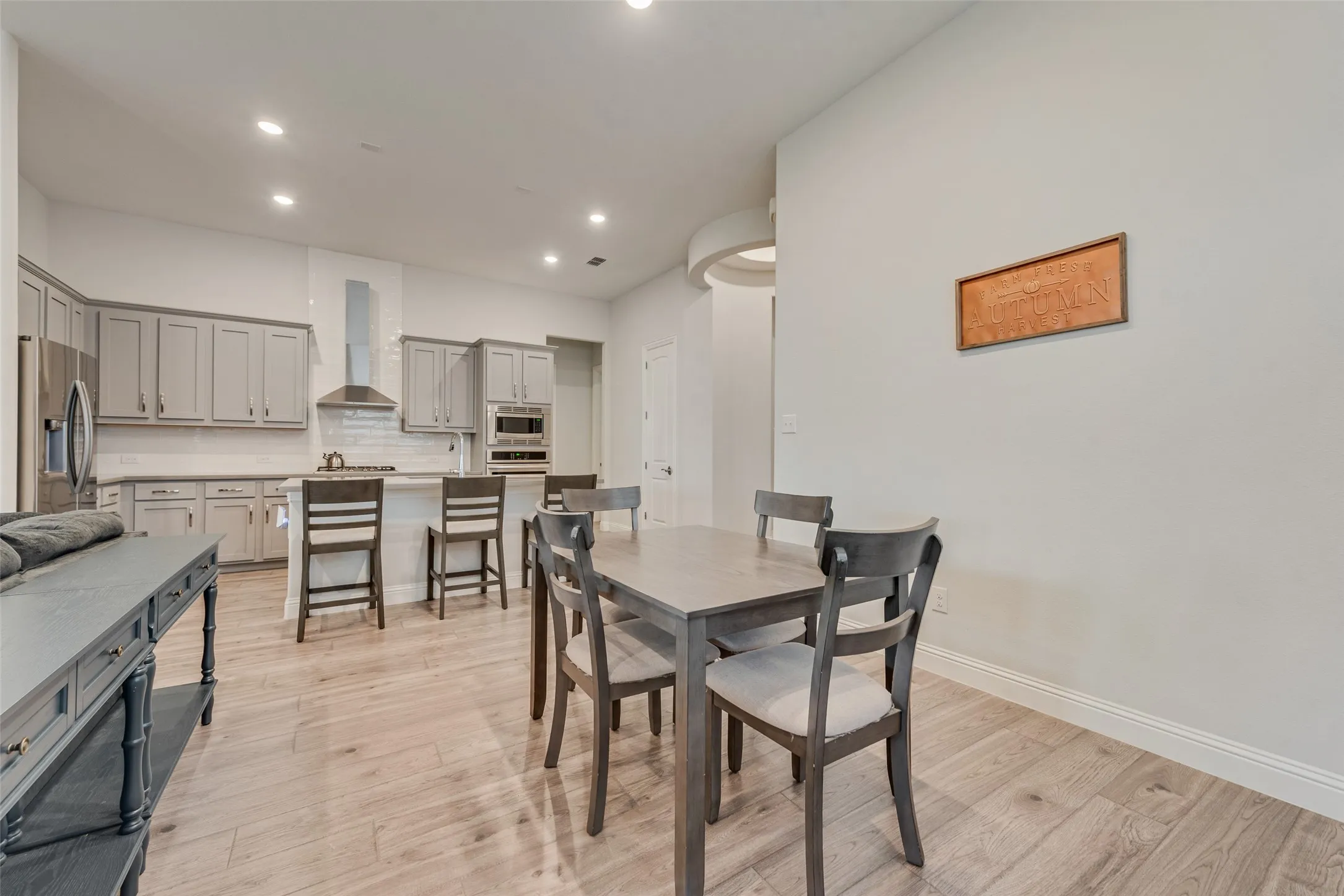 View into the dining room and kitchen with engineered hardwood floors, shaker cabinets, quartz countertops, and 11 ft ceilings at 1721 Pattenson Trl, Haslet, TX 76052 in Wellington subdivision