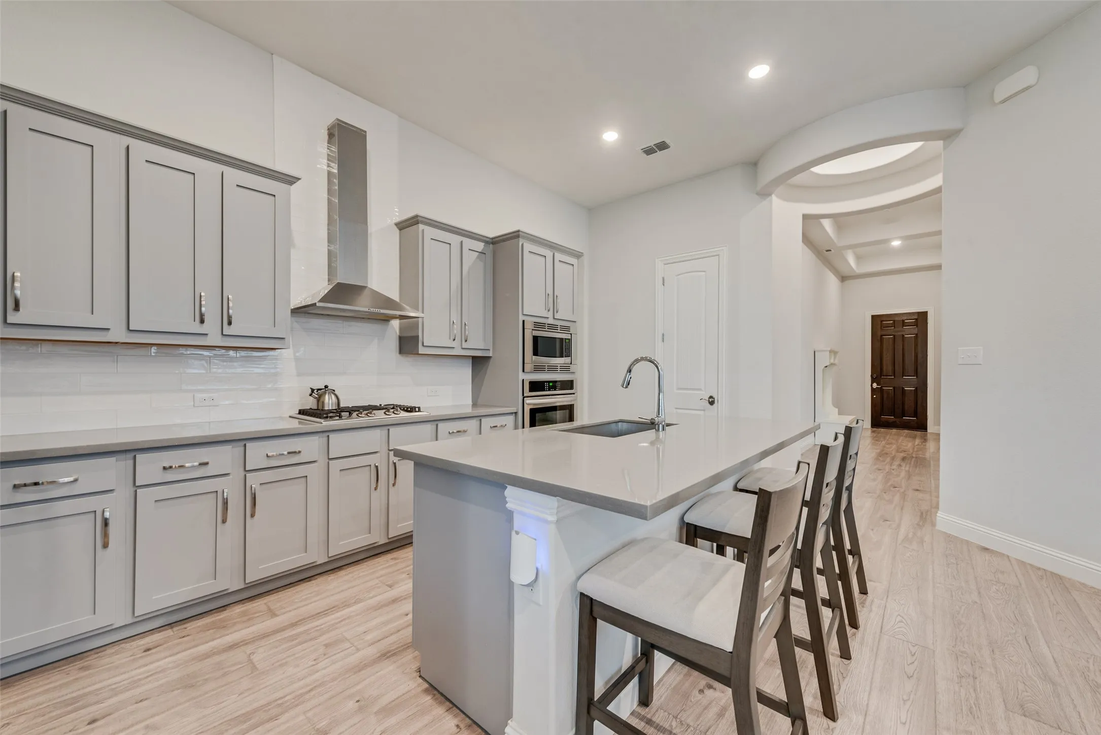 Open kitchen with engineered hardwood floors, shaker cabinets, quartz countertops,  and 11 ft ceilings at 1721 Pattenson Trl, Haslet, TX 76052 in Wellington subdivision