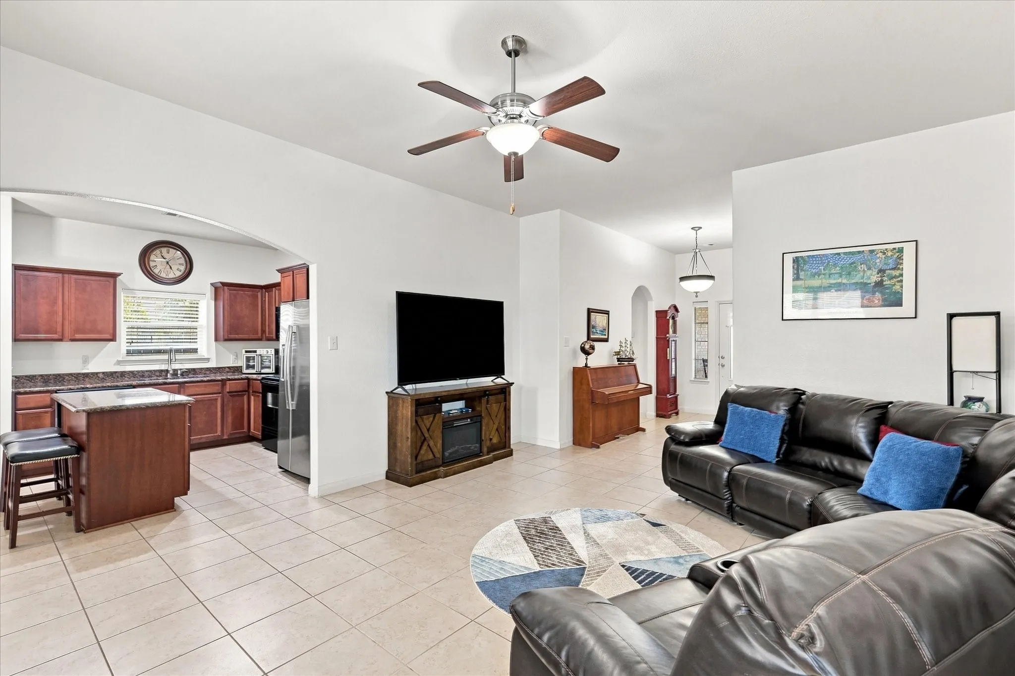 The expansive living room boasts tall ceilings and a modern ceiling fan, creating a bright and airy atmosphere. The open-concept design flows seamlessly into the kitchen, ideal for entertaining family and guests
