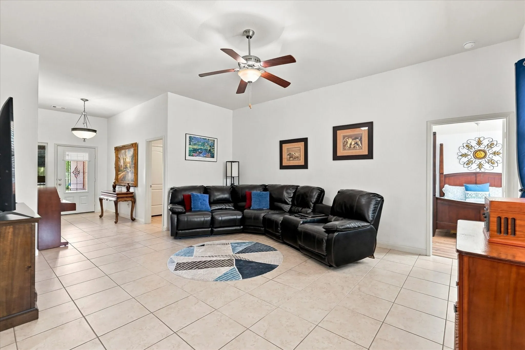 The expansive living room boasts tall ceilings and a modern ceiling fan, creating a bright and airy atmosphere. The open-concept design flows seamlessly into the kitchen, ideal for entertaining family and guests