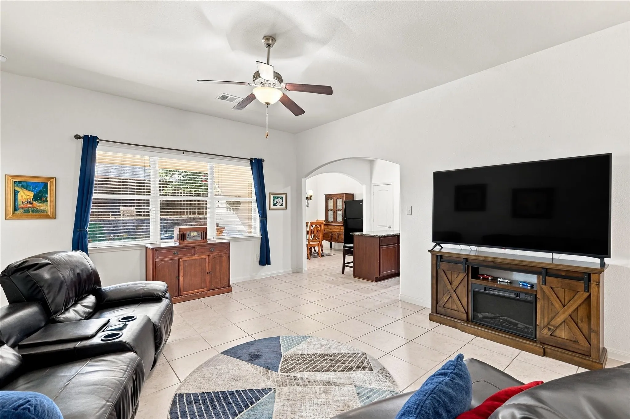 The bright living room features tall ceilings and shows how the durable tile in high-traffic zones transitions smoothly into the rest of the home's carpet-free spaces