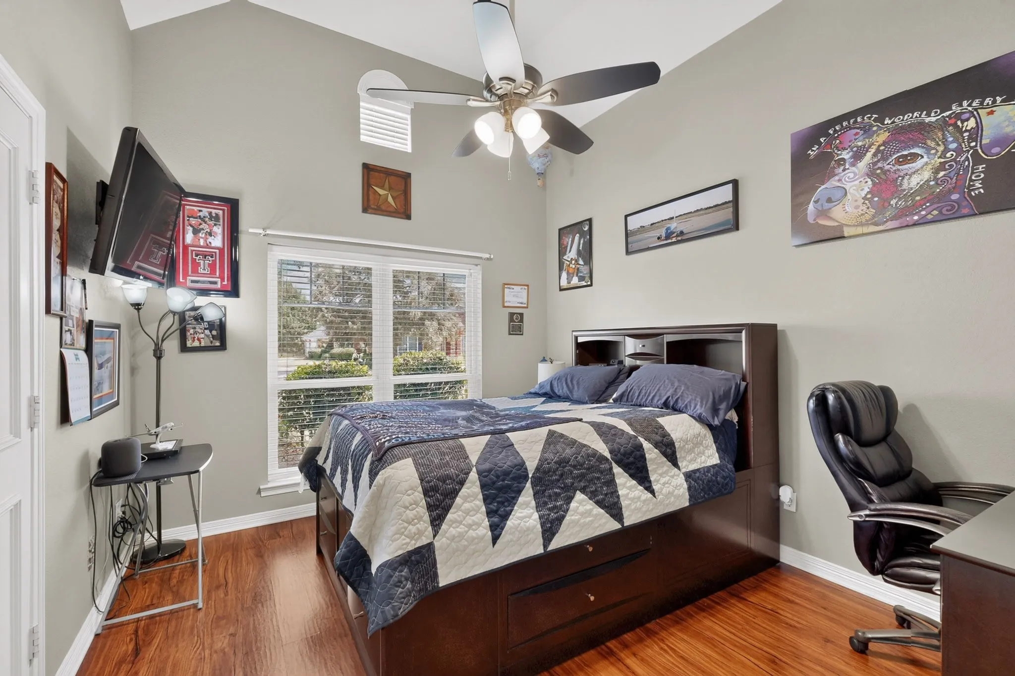 Vaulted ceiling with an integrated ceiling fan, wood-finish flooring, and large window with blinds