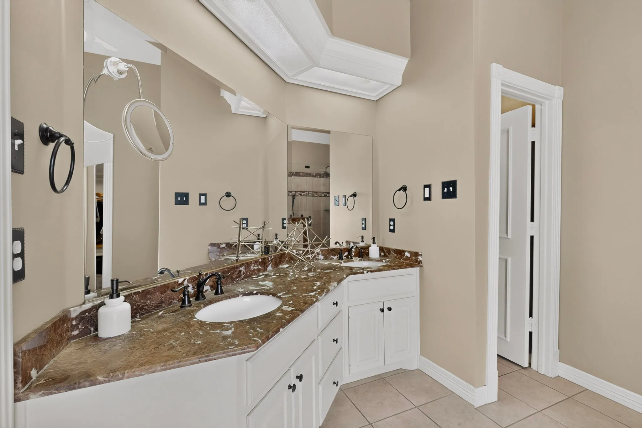 Dual vanity with a stone countertop, white cabinetry, undermount sinks, and dark hardware