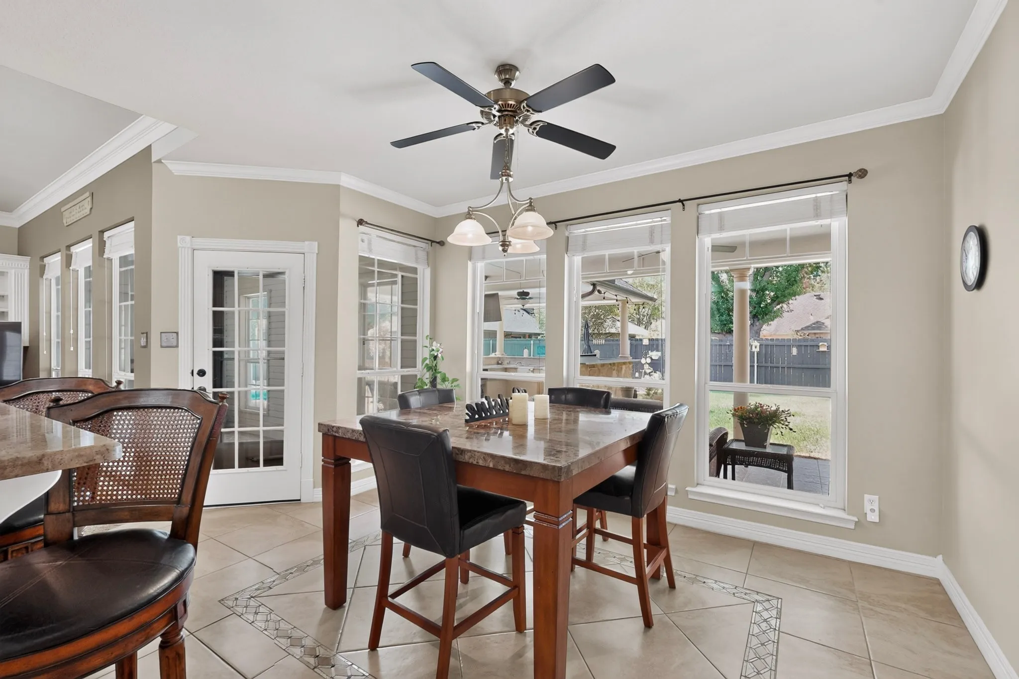 Bay window with multiple large pane windows, tile flooring with decorative inlay, French door with multiple glass panes, and a ceiling fan with integrated lighting