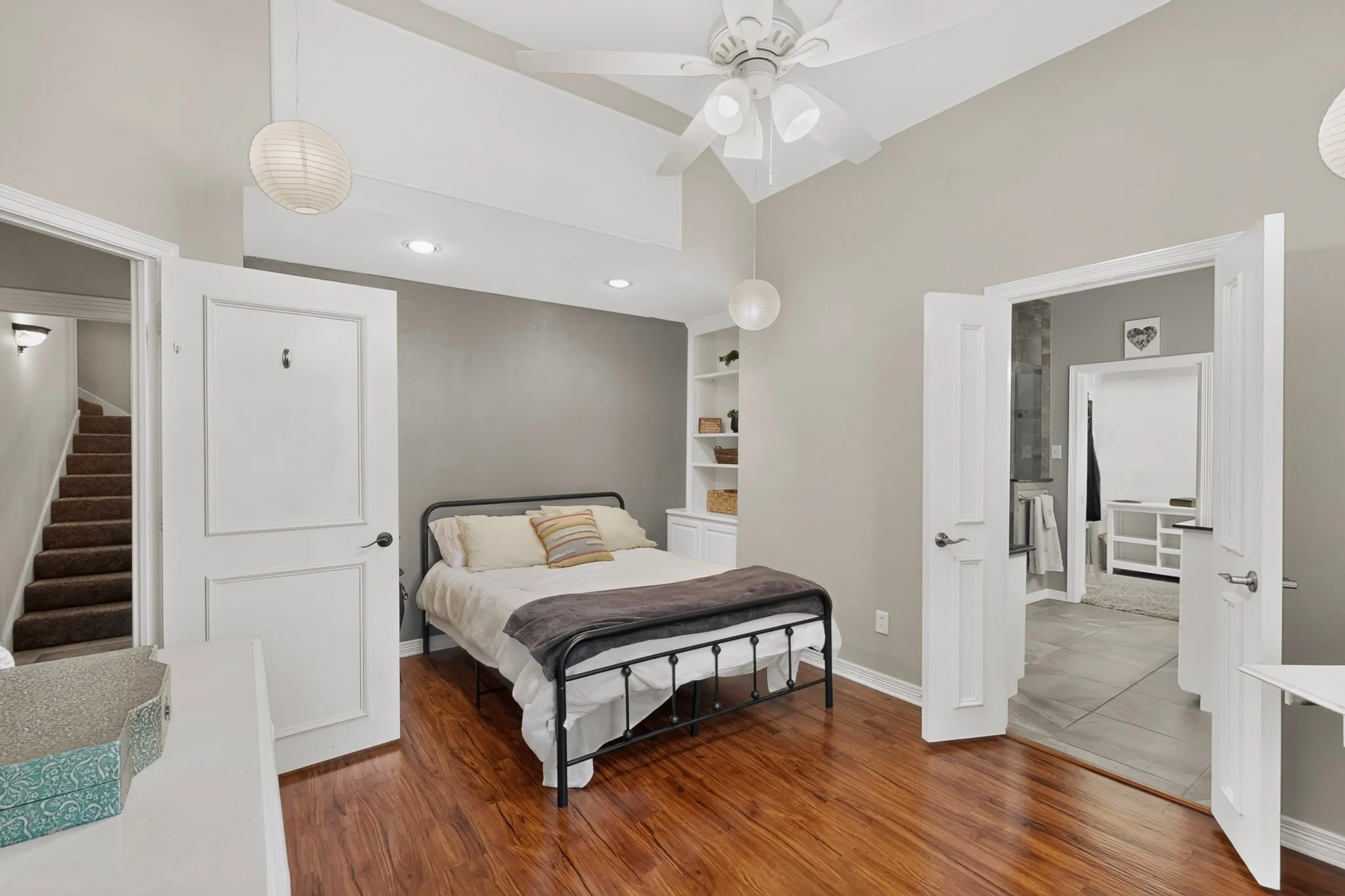 Vaulted ceiling with a ceiling fan, recessed lighting, wood-finish flooring, built-in shelving, and white paneled doors