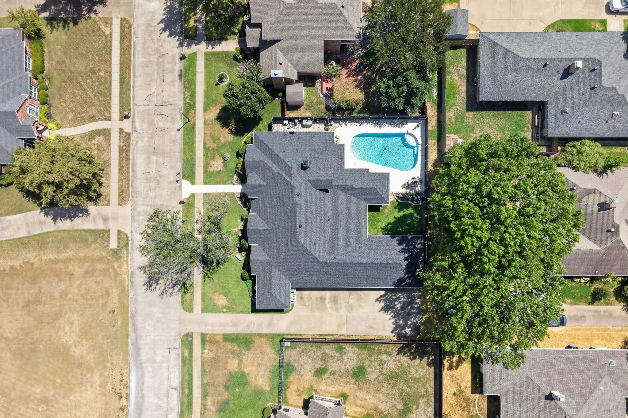 Expansive property featuring a dark-toned roof, a swimming pool, and mature trees