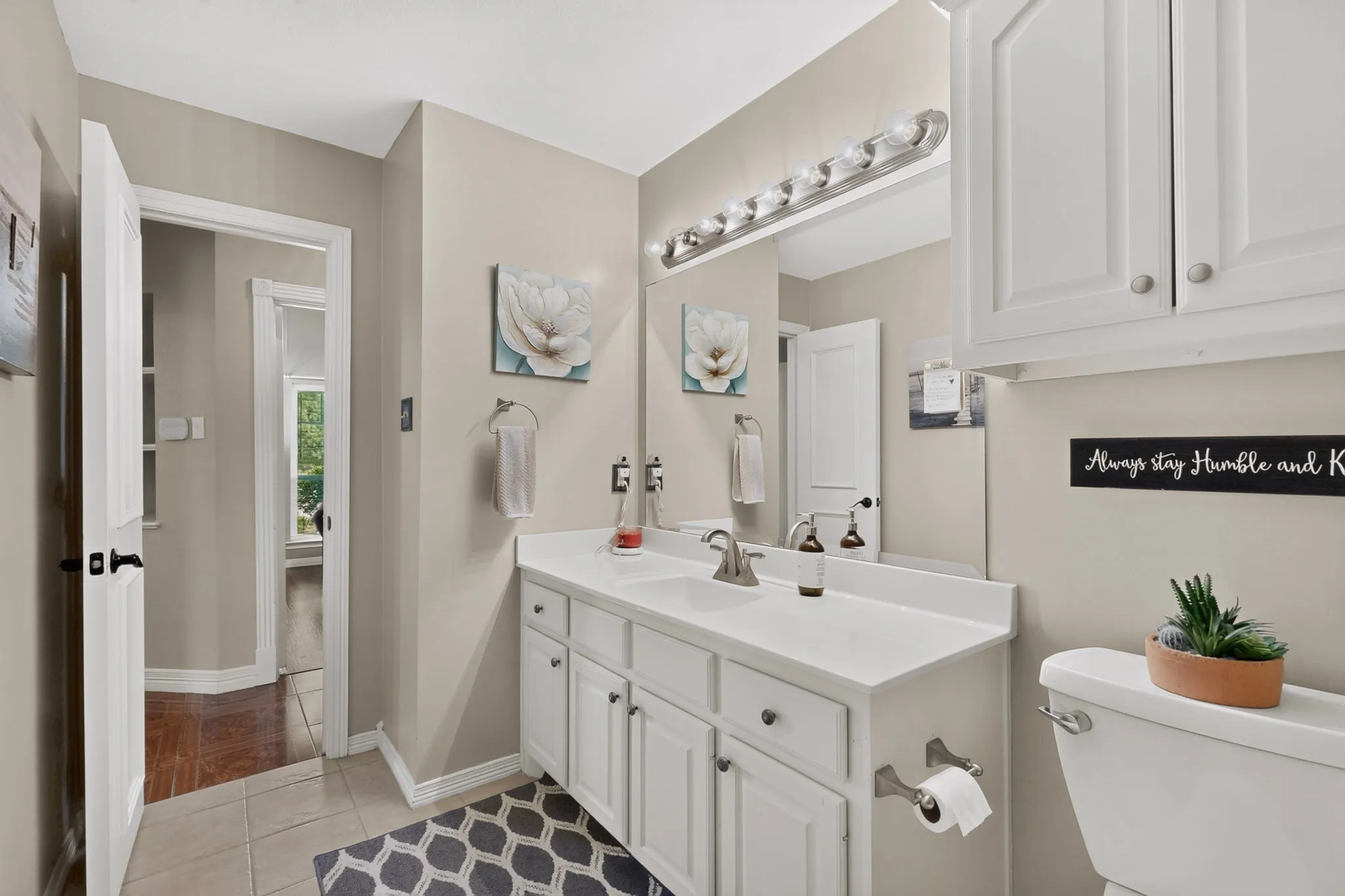 Dual-sink vanity with white cabinetry, integrated countertop, and mounted mirror