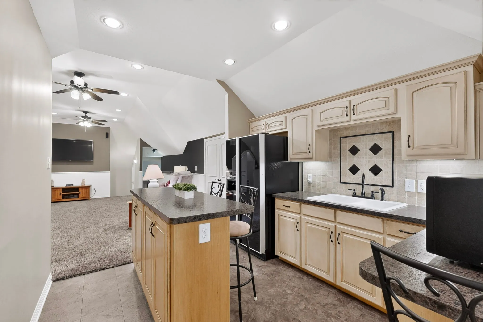 Kitchen featuring light-toned cabinetry, dark countertops, and a tile backsplash
