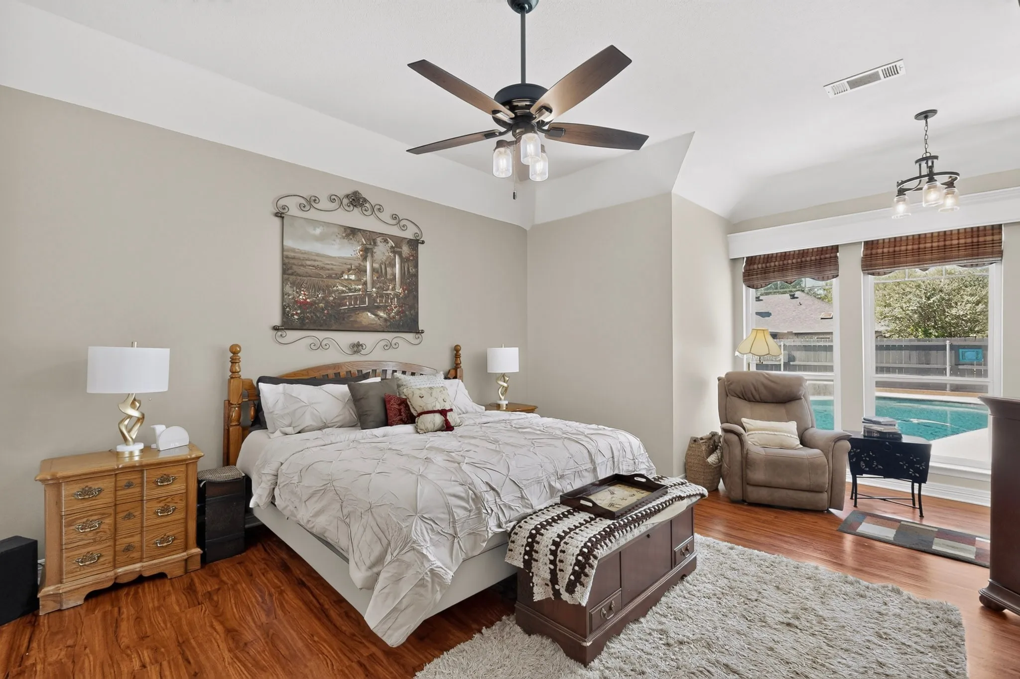 Tray ceiling, wood-finish flooring, ceiling fan with integrated lighting, multiple windows with blinds, and recessed lighting