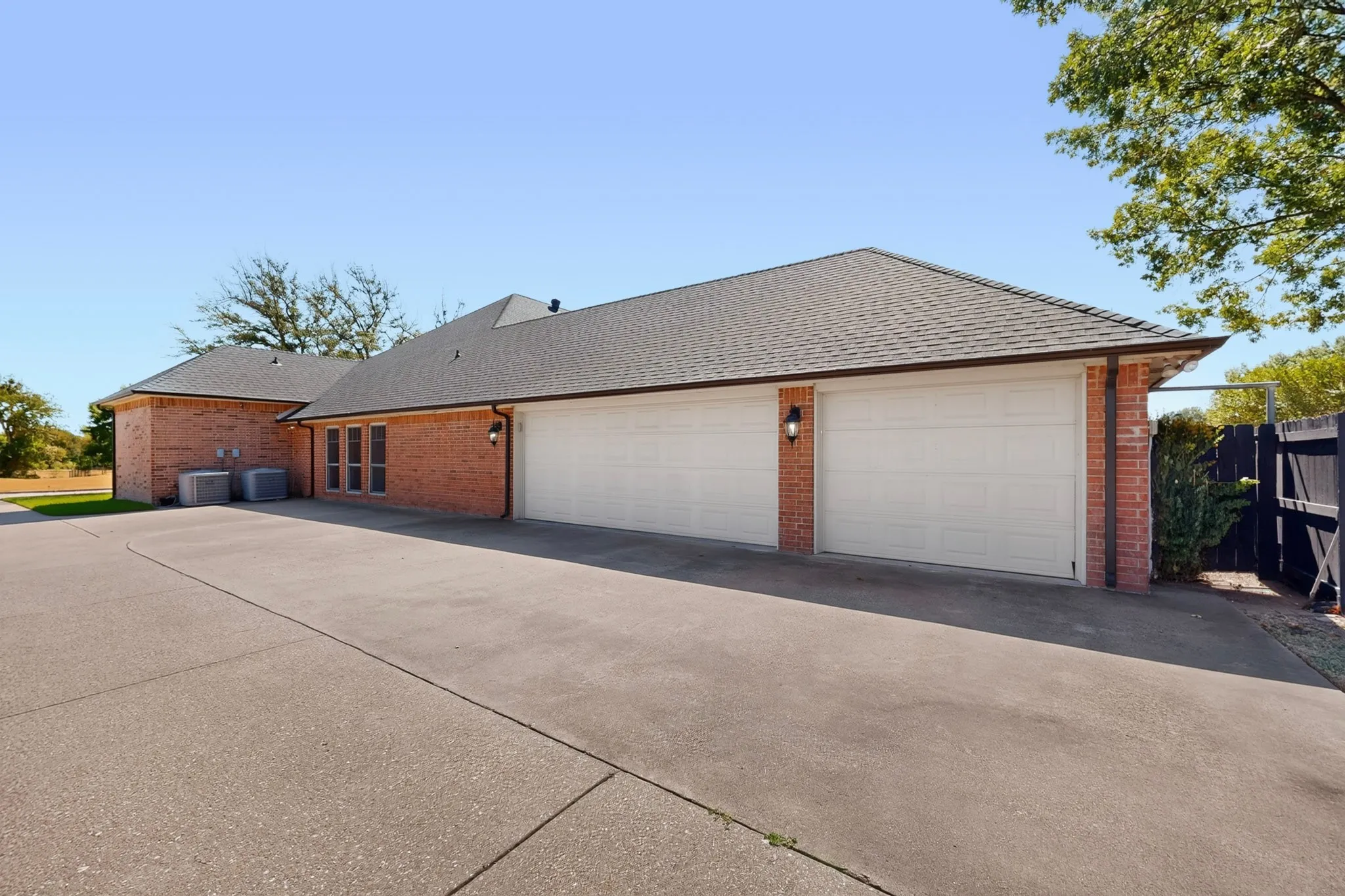 Brick exterior, asphalt shingle roof, two-car garage, concrete driveway, and exterior lighting fixtures