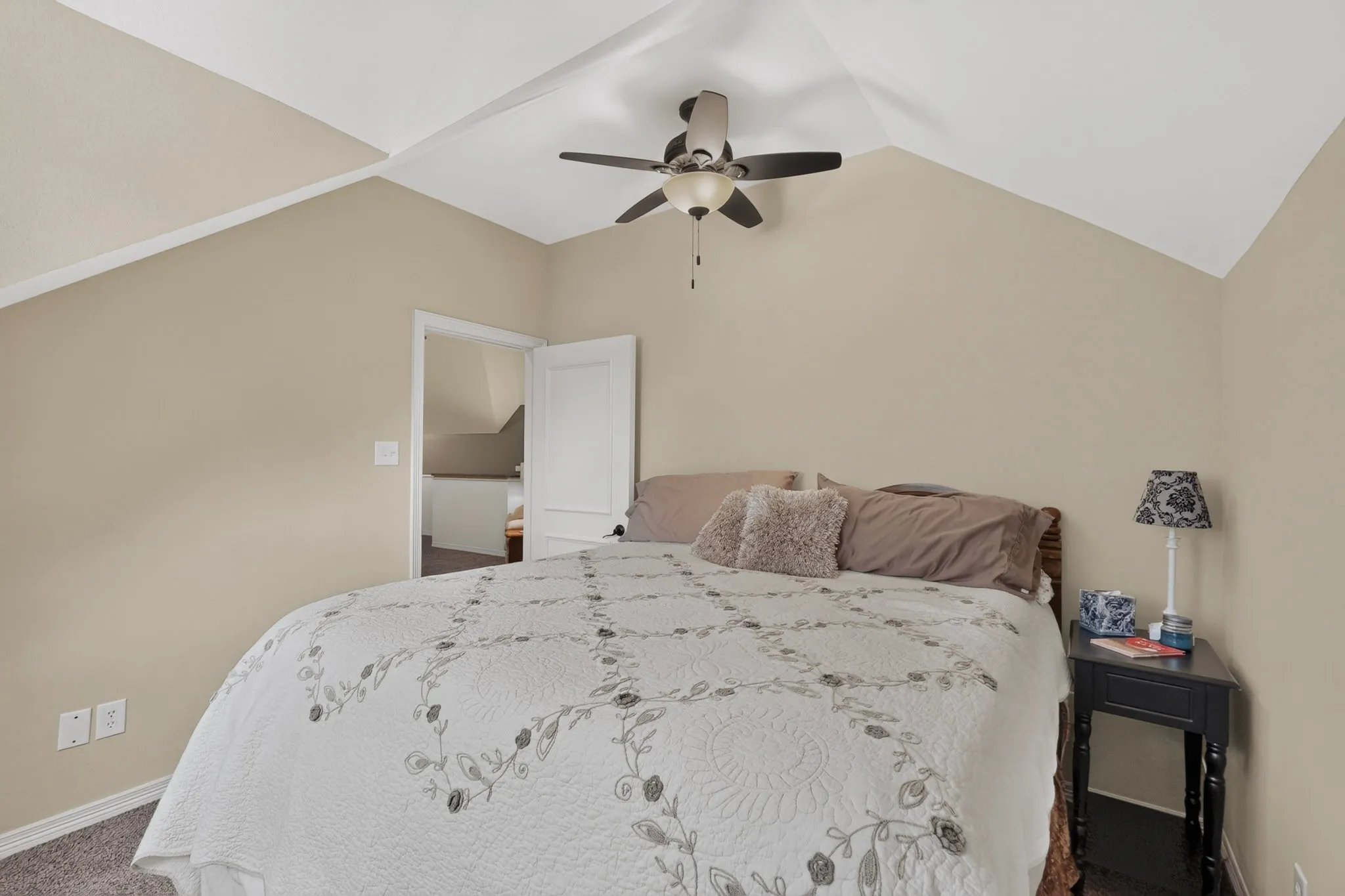 Vaulted ceiling with a ceiling fan, neutral wall paint, and carpeted flooring