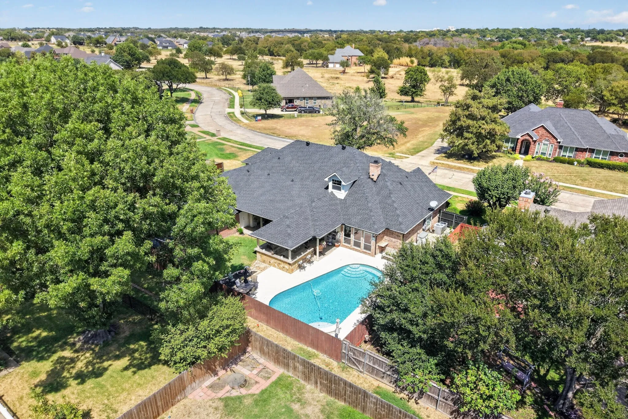 Residential property with a dark shingle roof, an outdoor swimming pool, and a fenced yard