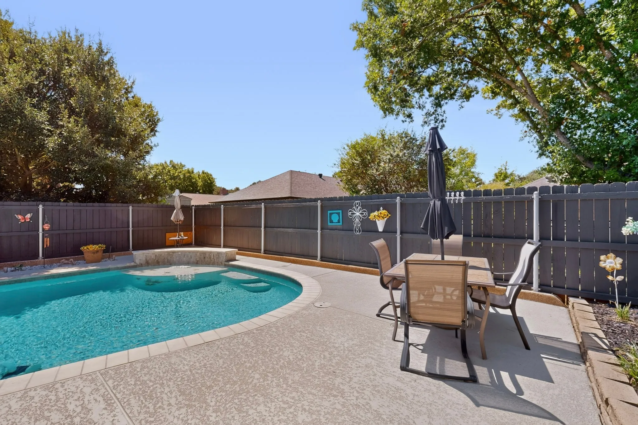 Private backyard featuring a curved swimming pool, integrated spa, and concrete patio