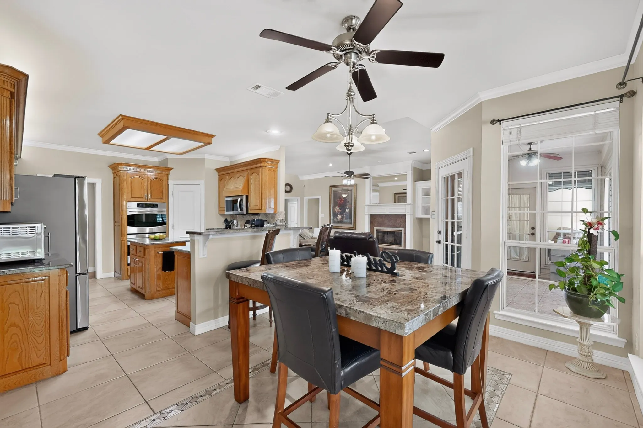 Tile flooring, wood cabinetry, built-in stainless steel appliances, breakfast bar, and a dining area with a window