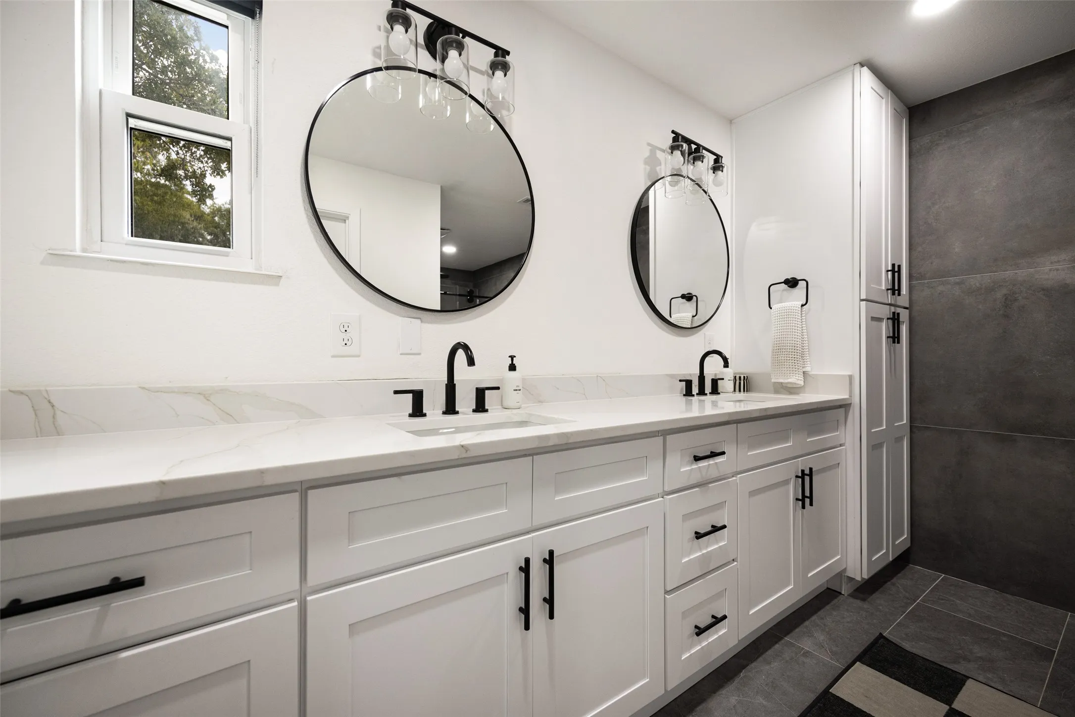 Dual vanity with white cabinetry, matte black hardware, and stone-finish countertops