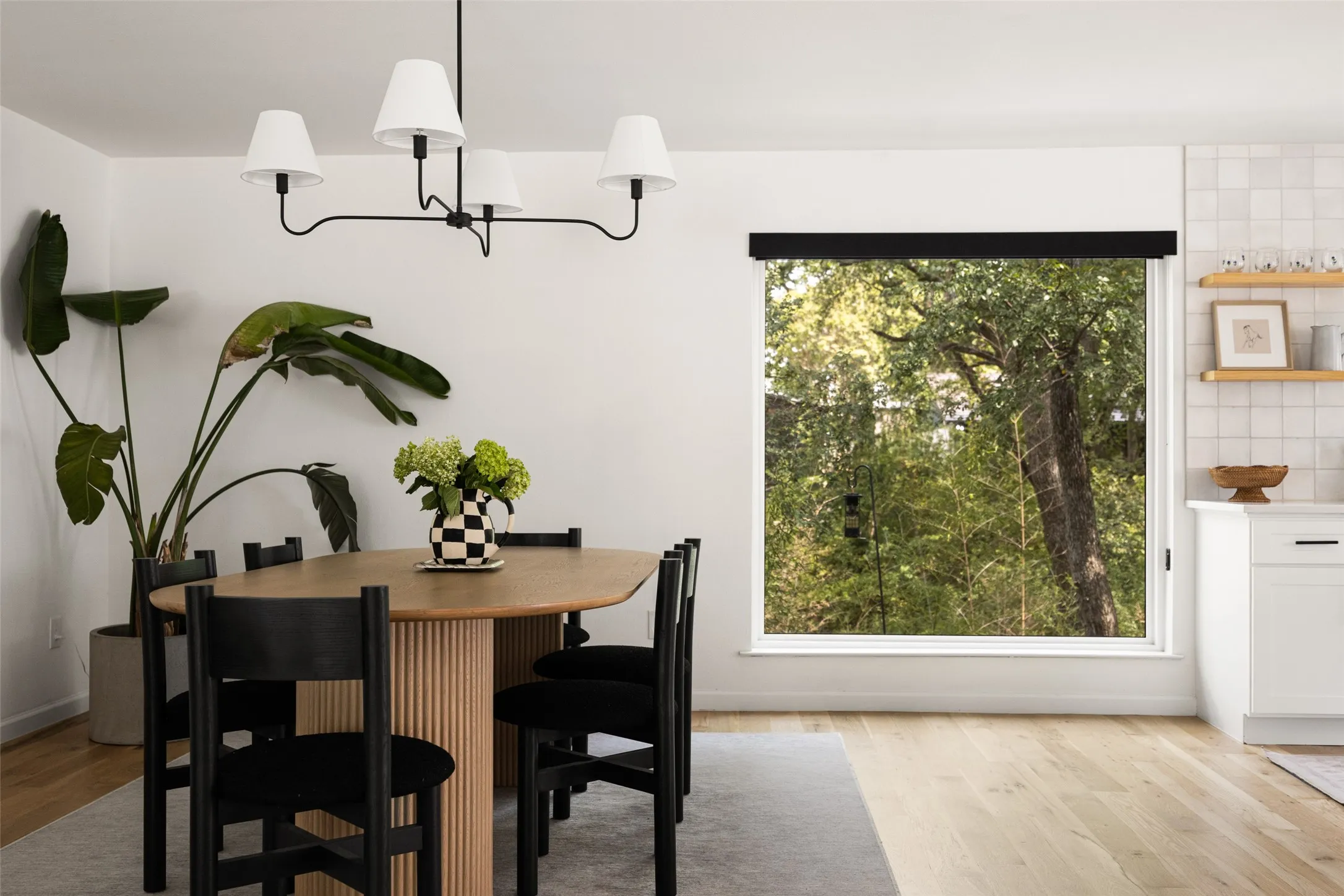 Wood-finish flooring, white walls, and a large window with roller shade