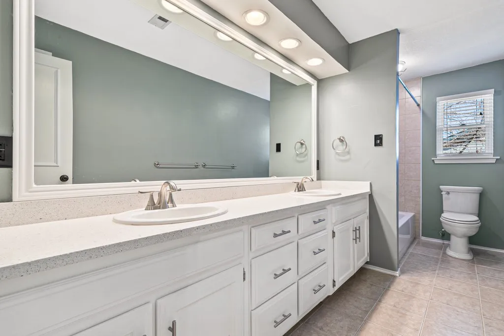 Full bathroom featuring double vanity, light tile patterned floors, and shower / bathtub combination