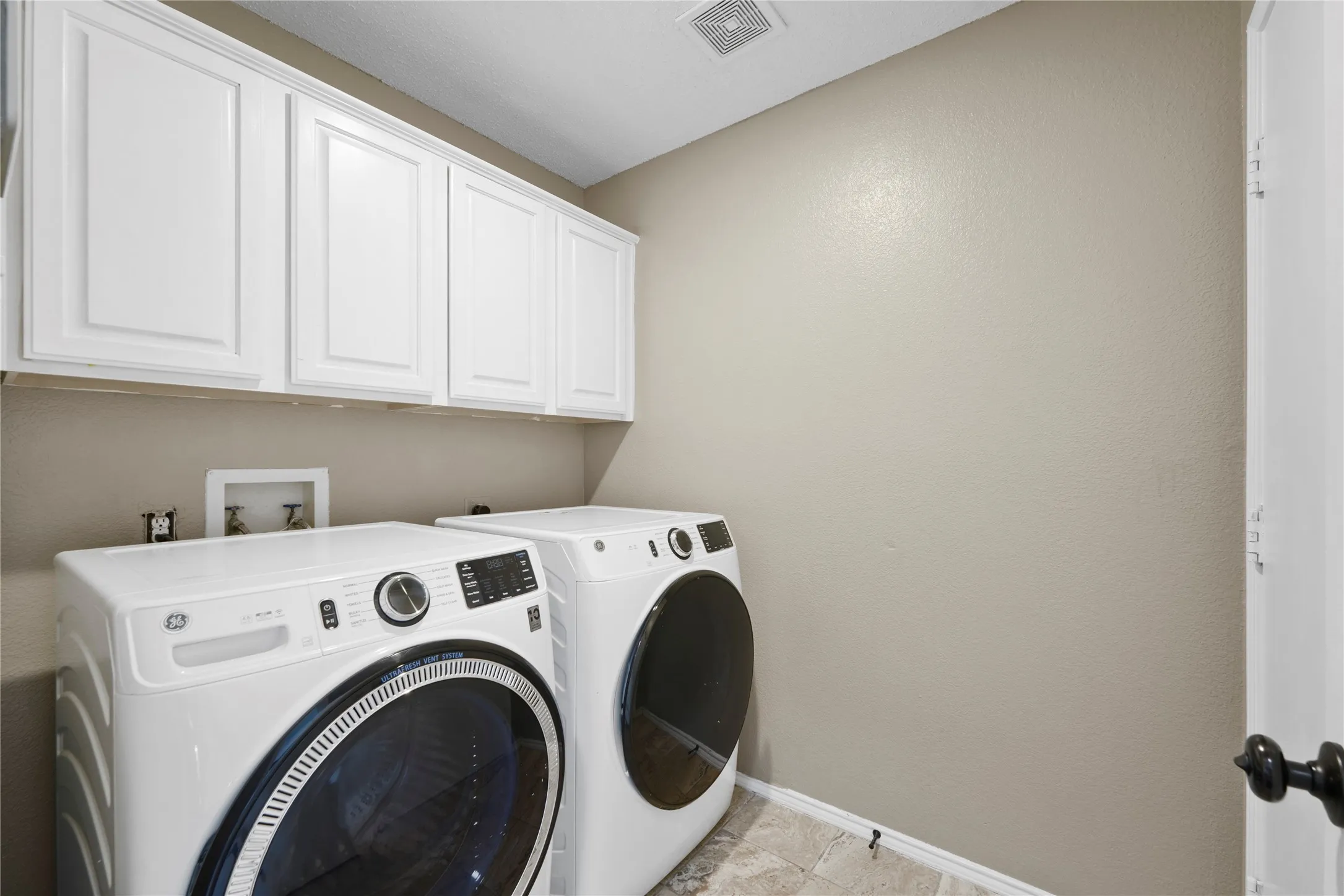 White cabinetry, textured wall finish, and tile flooring