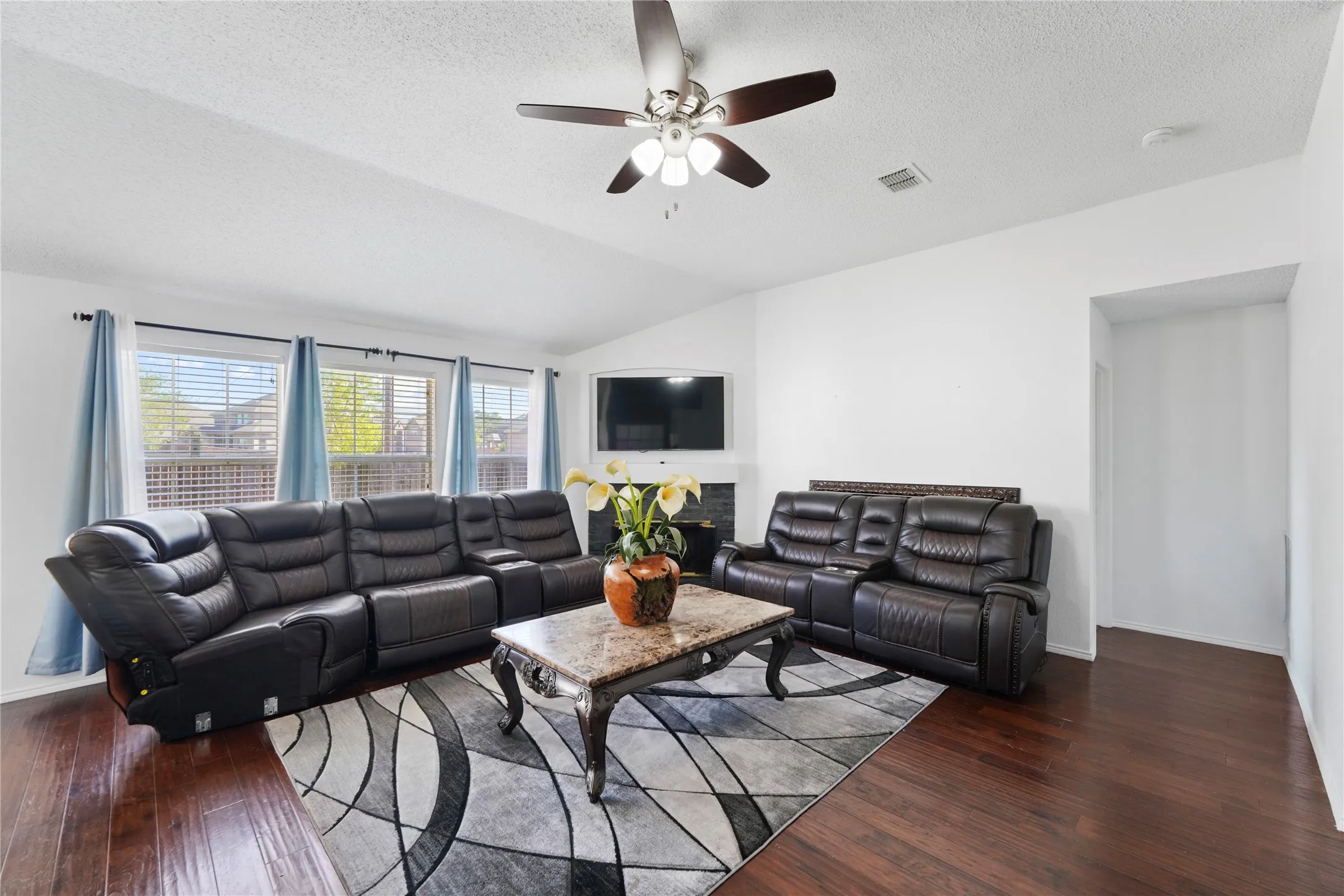 Vaulted ceiling with a ceiling fan, dark wood-finish flooring, and multiple windows with blinds