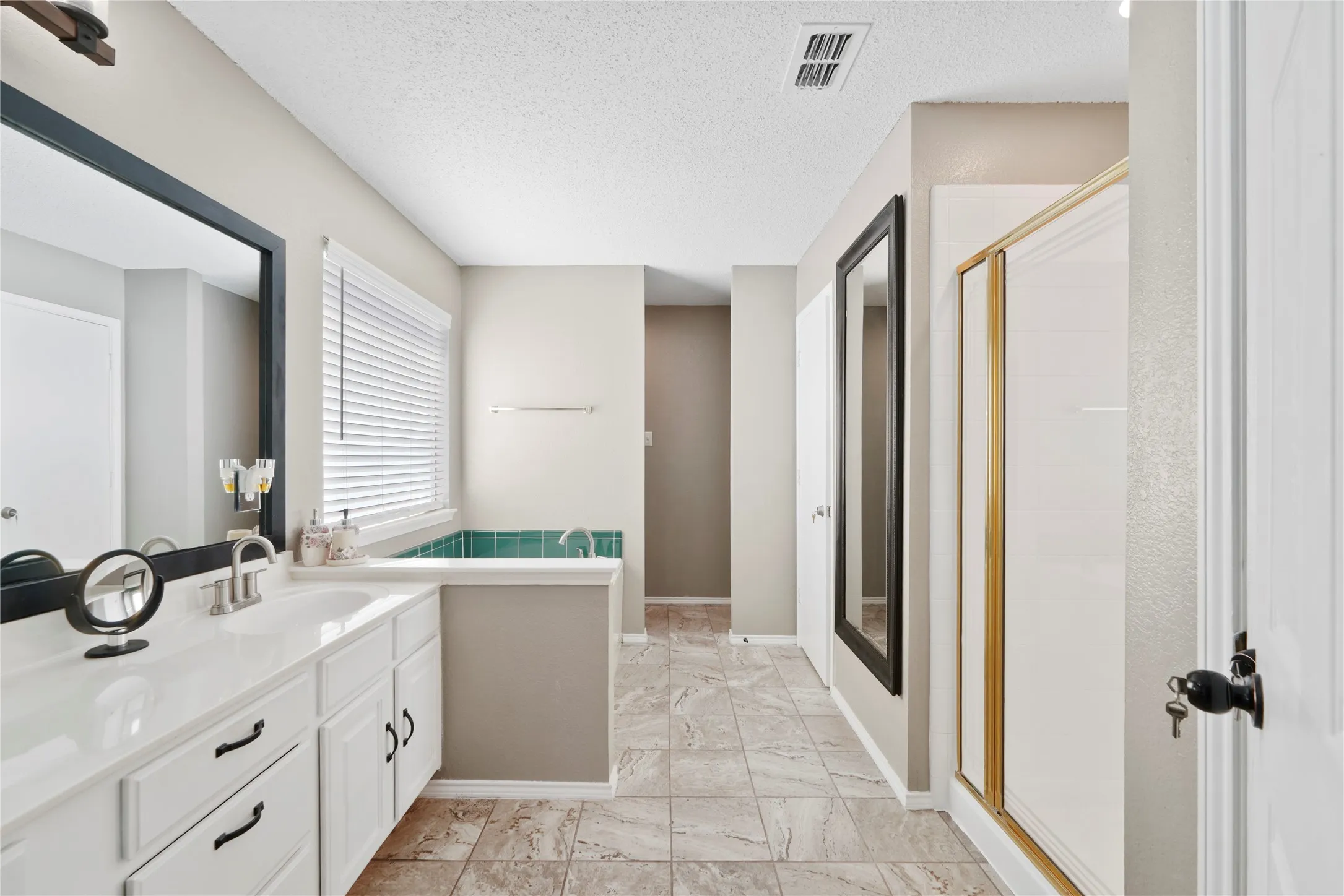 Double vanity with individual sinks, white cabinetry, and matte black hardware