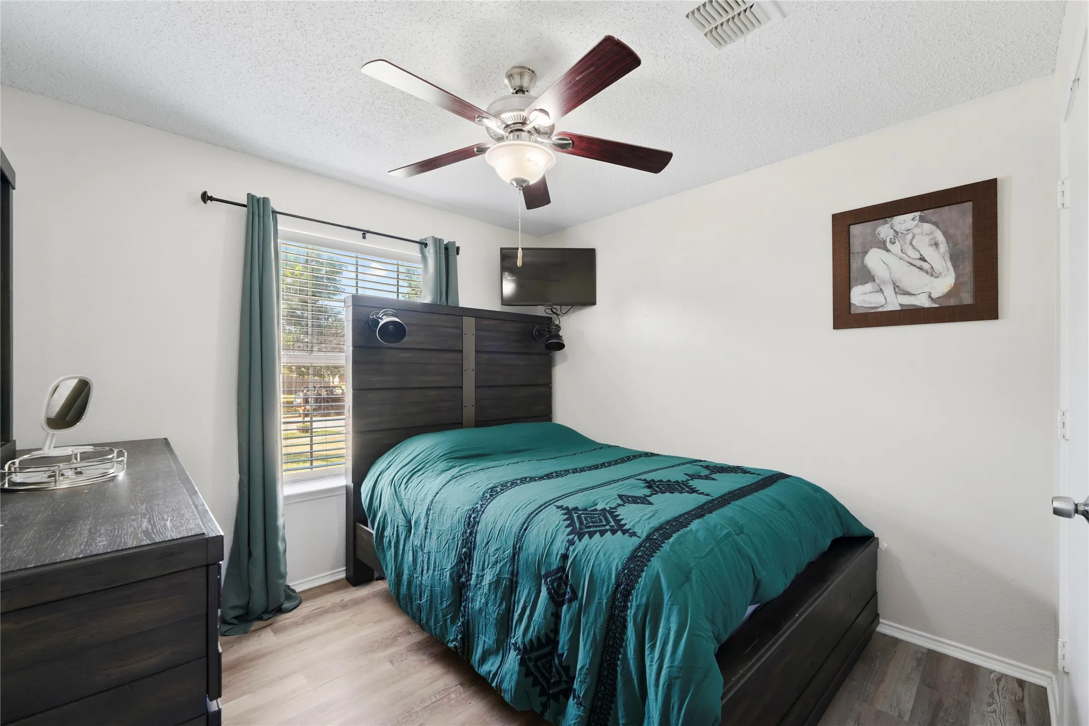 Recessed window with blinds, wood-finish flooring, and a ceiling fan with light fixture
