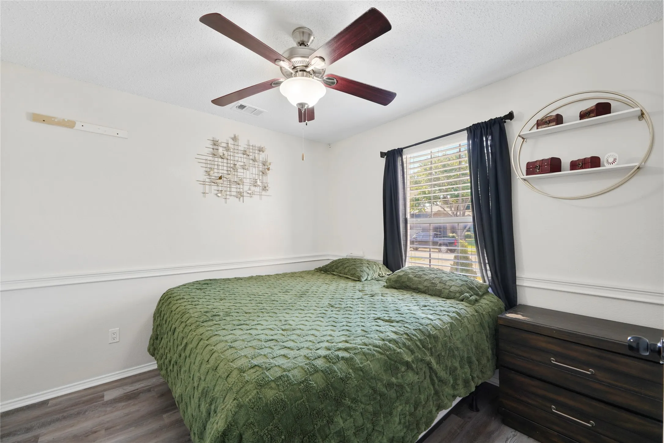 Wood-finish flooring, ceiling fan with integrated lighting, window with blinds, and white wall trim