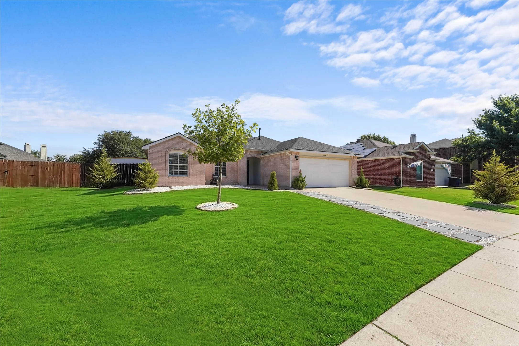 Brick exterior with arched entry and window, attached garage, and concrete driveway