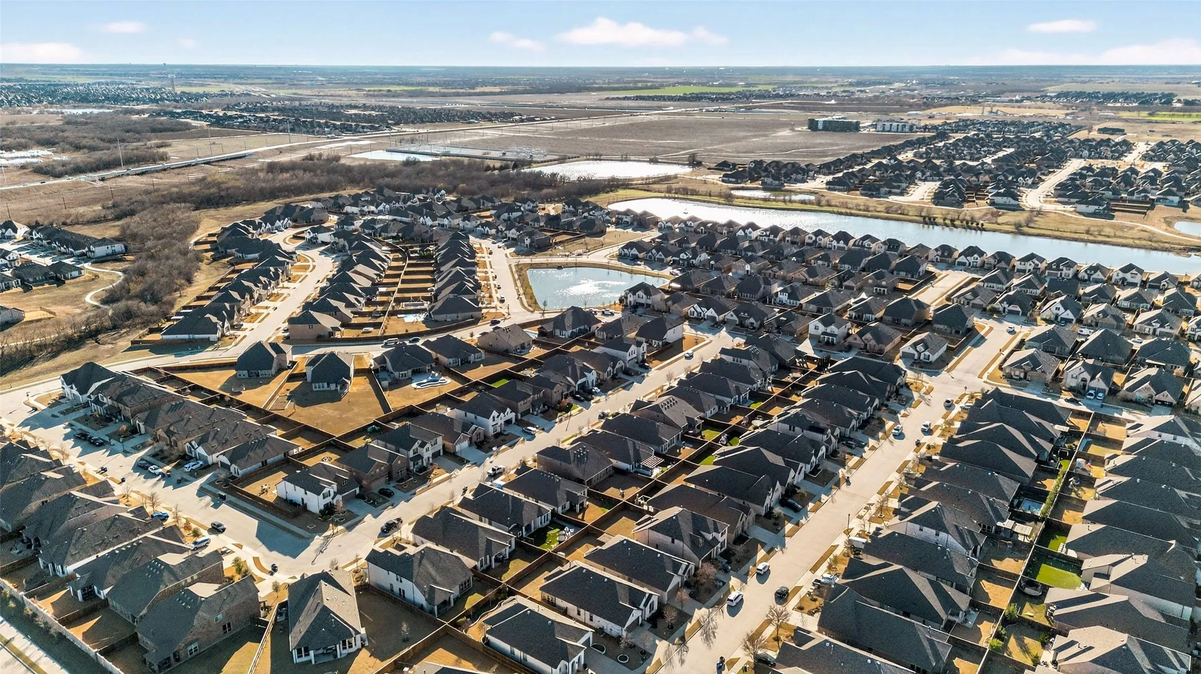 Residential development with multiple single-family homes, dark shingle roofs, and paved streets
