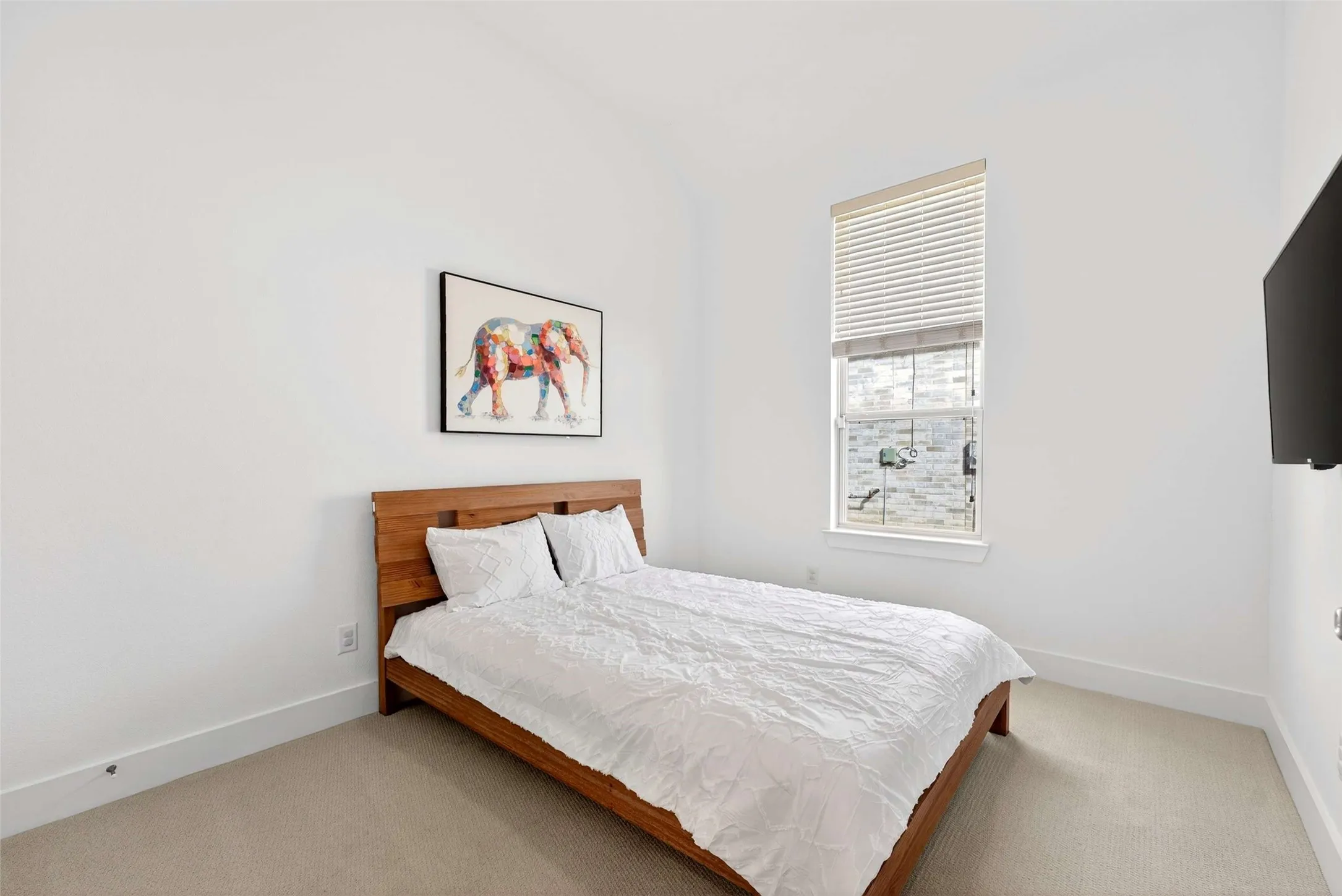 Vaulted ceiling room featuring carpet flooring, a tall vertical window with blinds, and a wall-mounted display