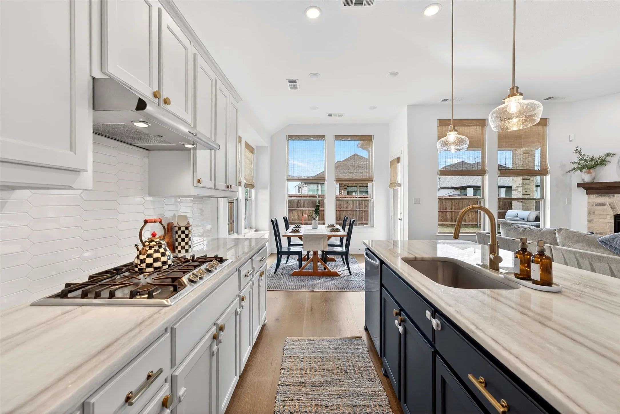 Kitchen featuring white upper cabinetry, dark lower cabinetry, light stone countertops, a gas range, and a built-in sink with a gooseneck faucet