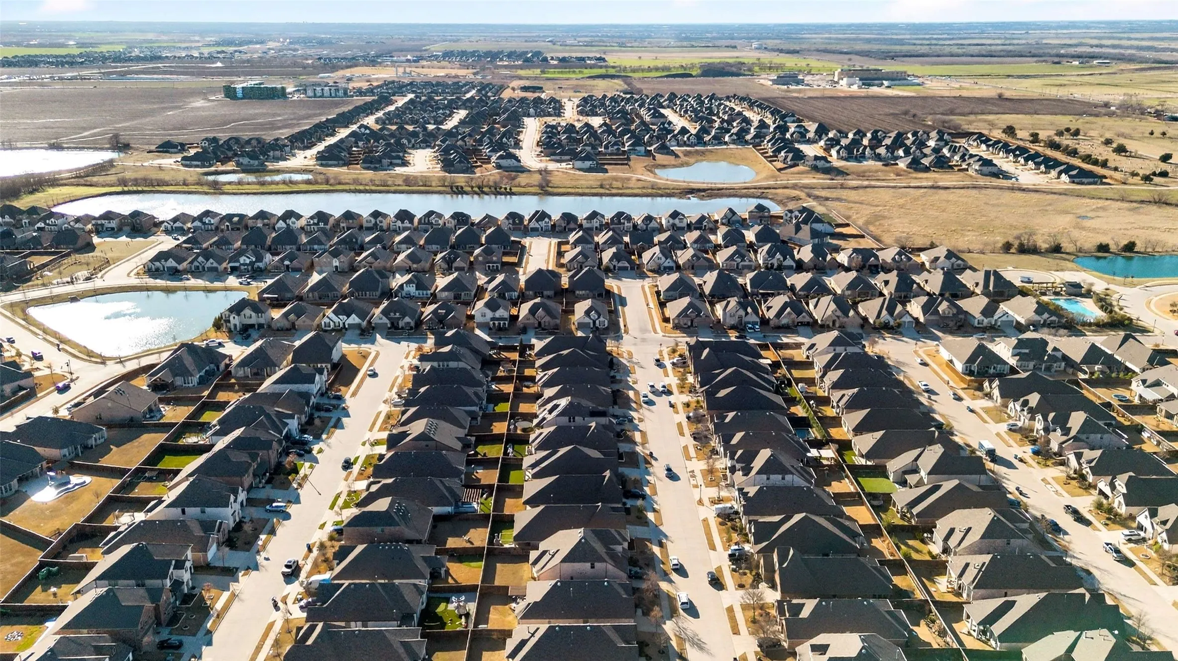 Expansive residential development featuring numerous single-family homes, multiple retention ponds, and established roadways