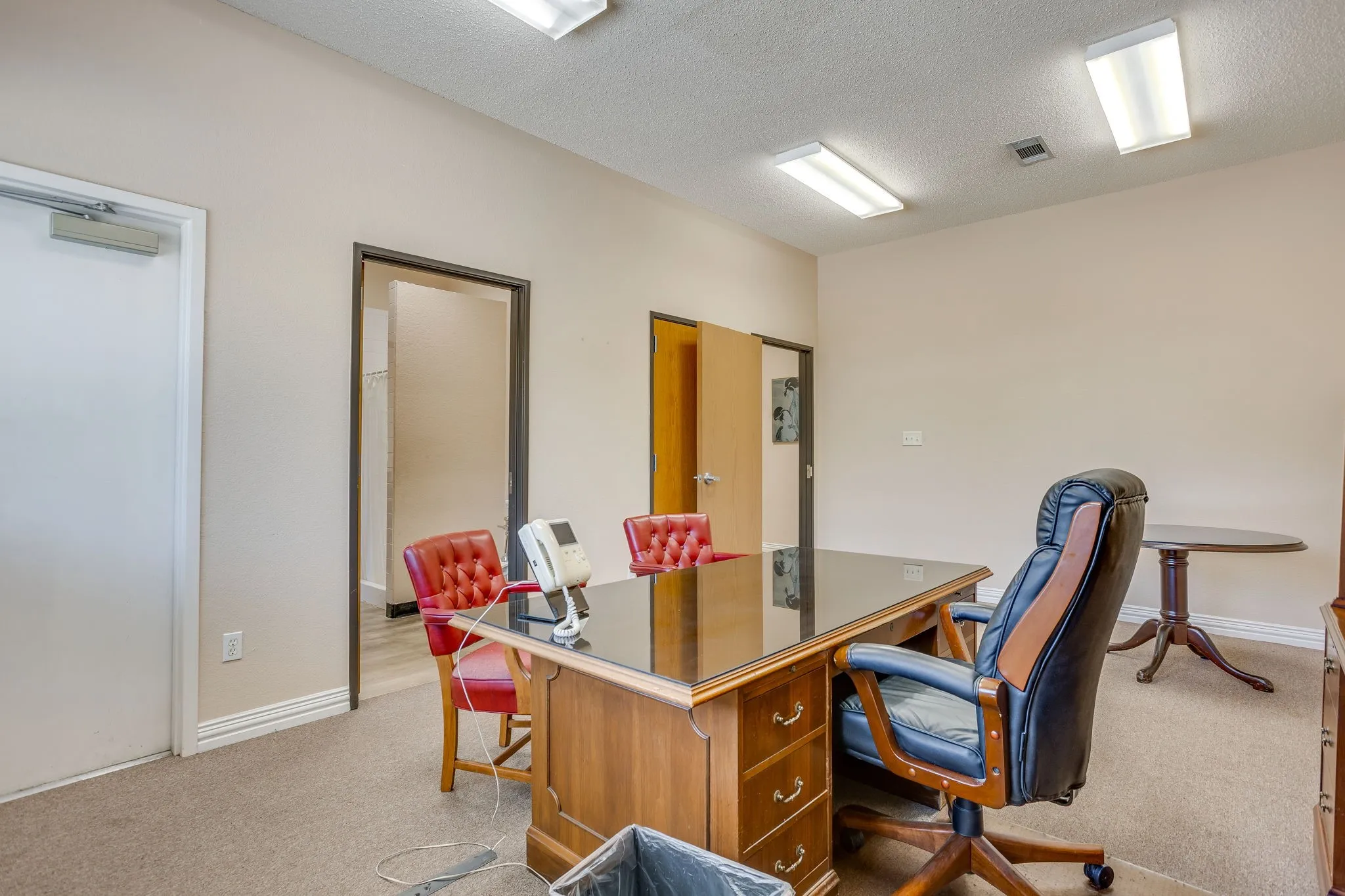 Neutral wall paint, ceiling-mounted fluorescent lighting, and two interior doorways