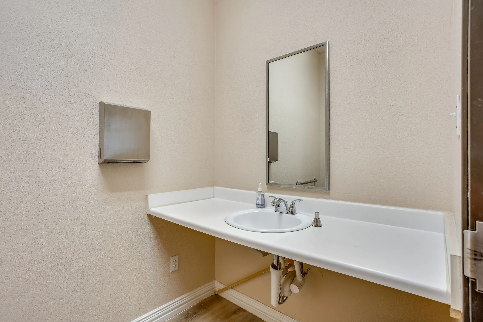 Wall-mounted rectangular mirror positioned above a spacious countertop with an integrated white sink