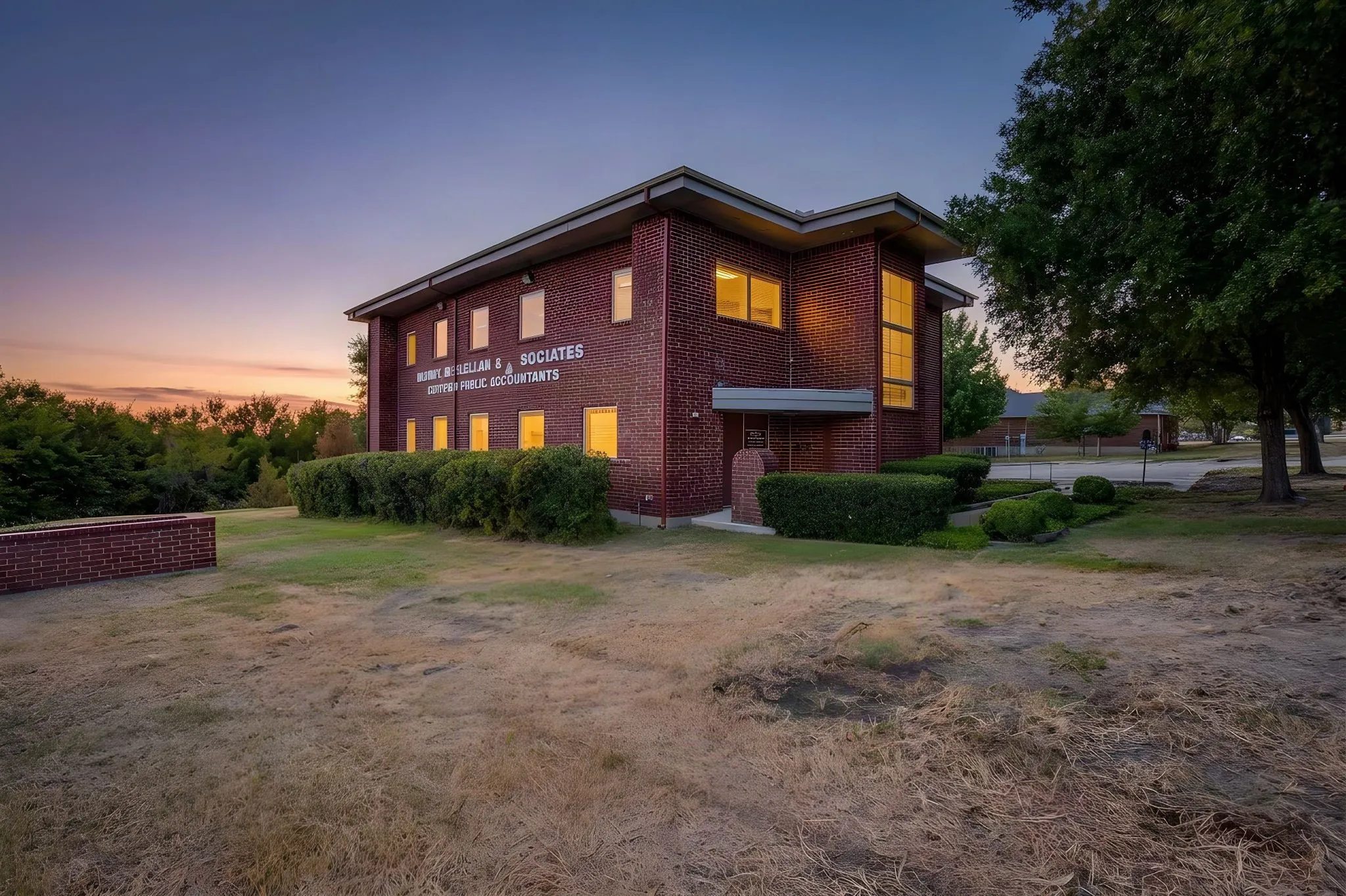 Brick exterior with multiple windows, architectural overhangs, and established landscaping