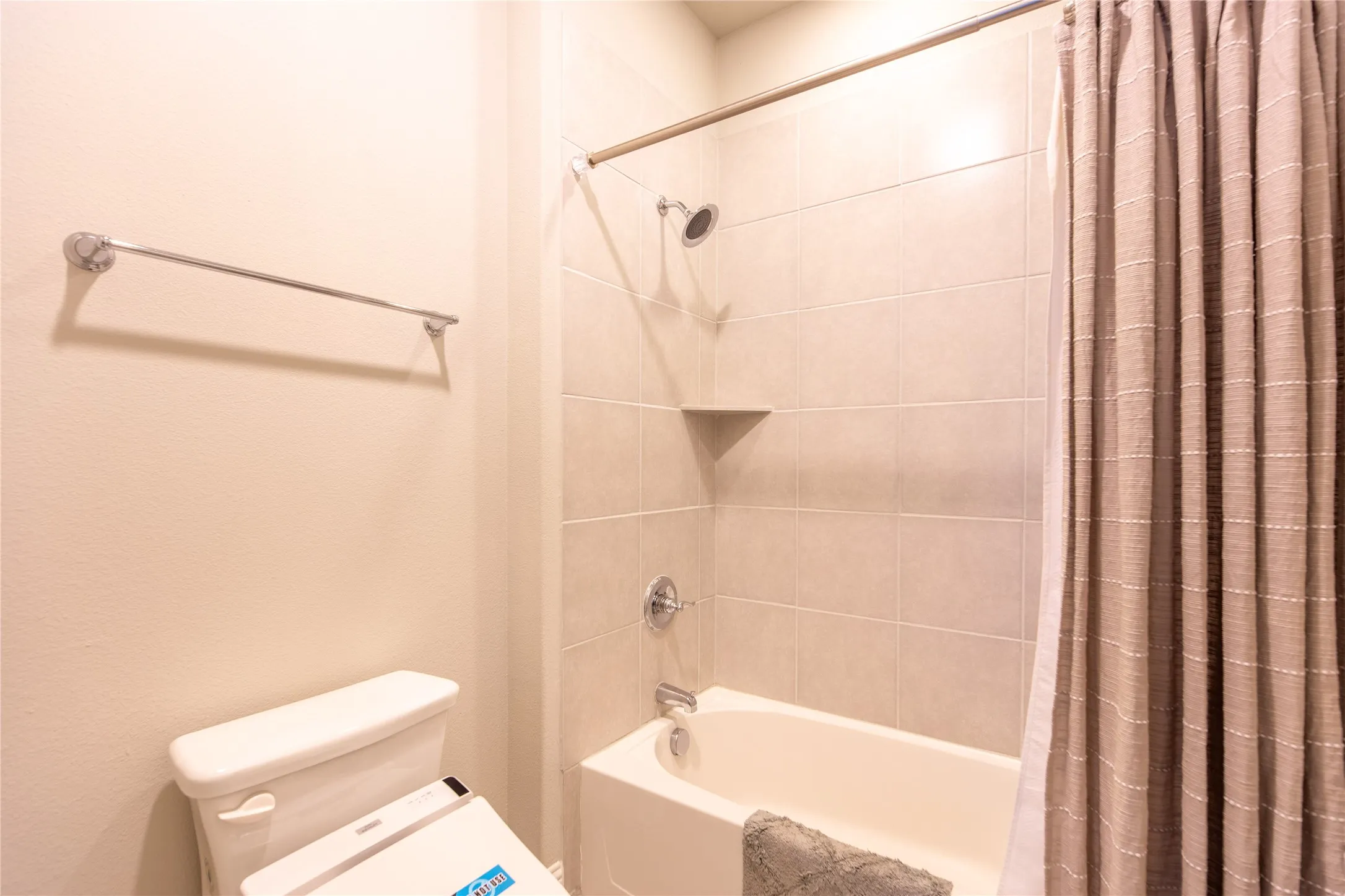 Bathtub with tile surround, shower fixture, and wall-mounted towel bar