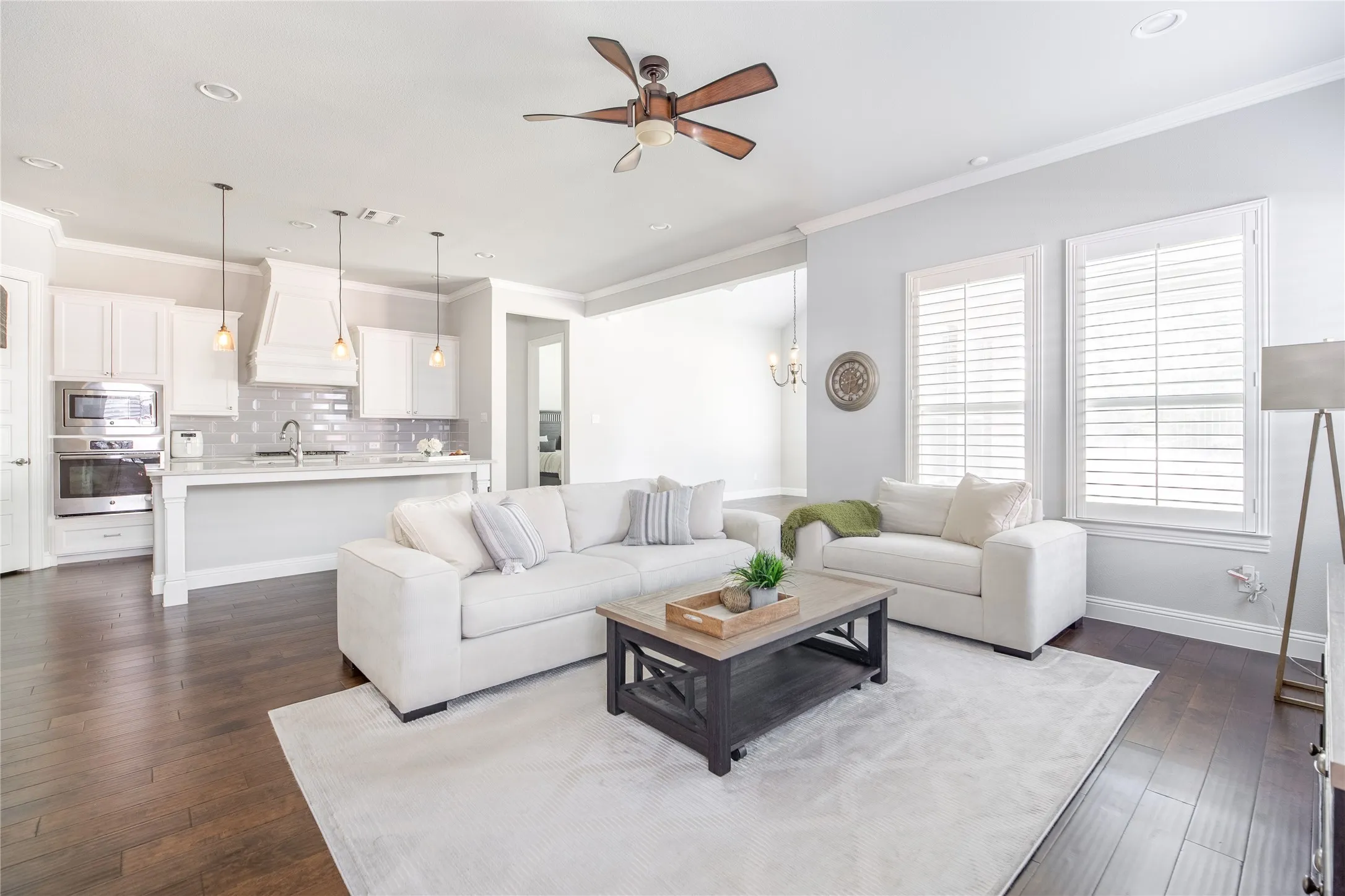 Open-concept living area featuring dark wood-finish flooring, white plantation shutters, and recessed lighting