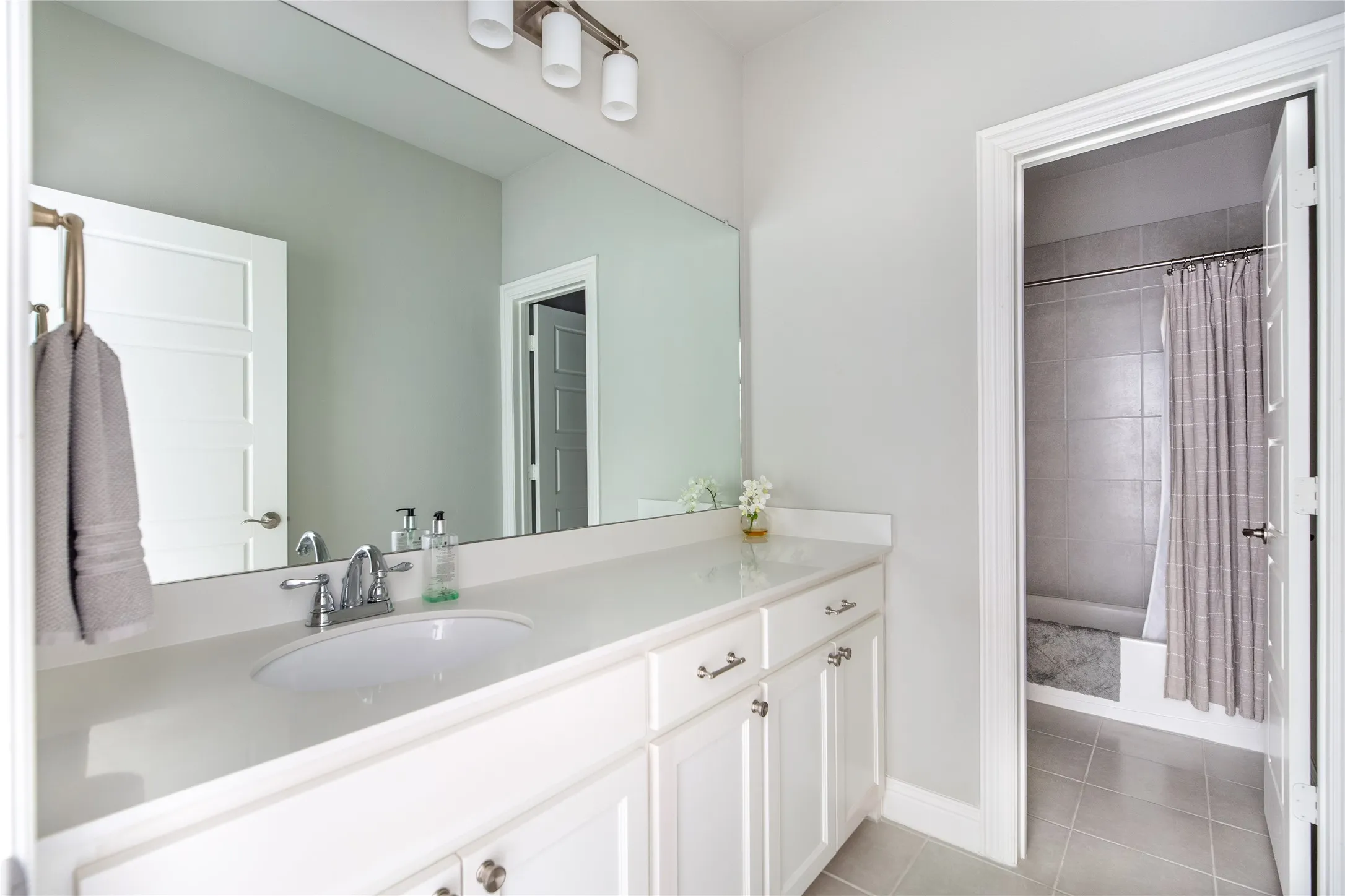 White shaker-style vanity with chrome hardware, an integrated basin, and a light-toned countertop