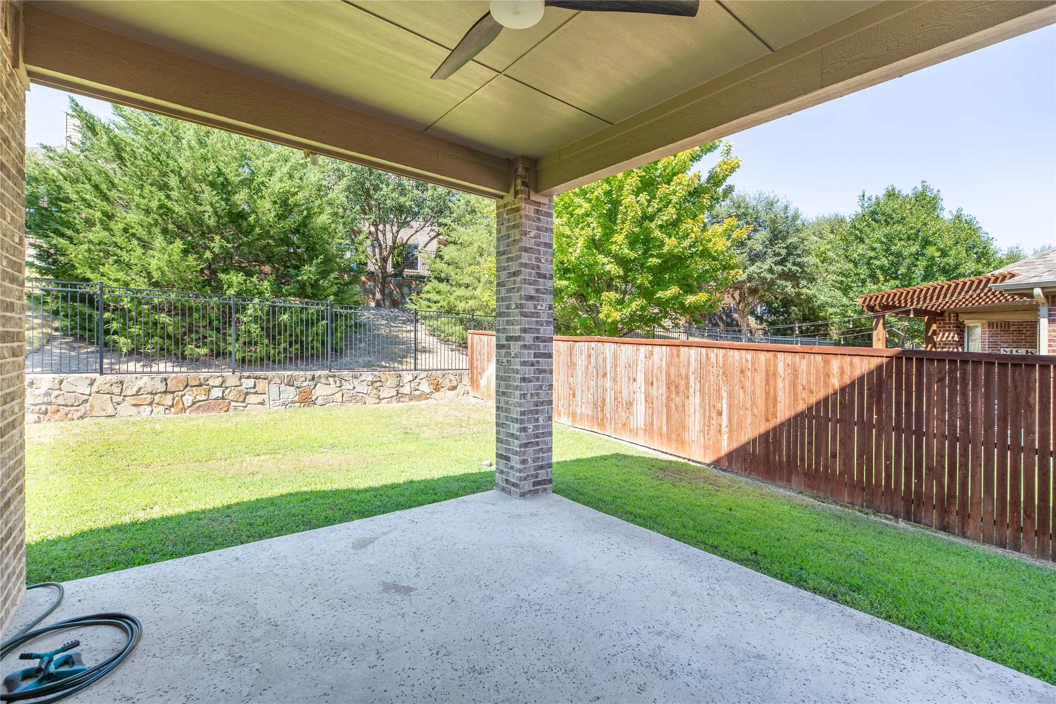 Covered patio with a ceiling fan, brick support columns, and concrete flooring