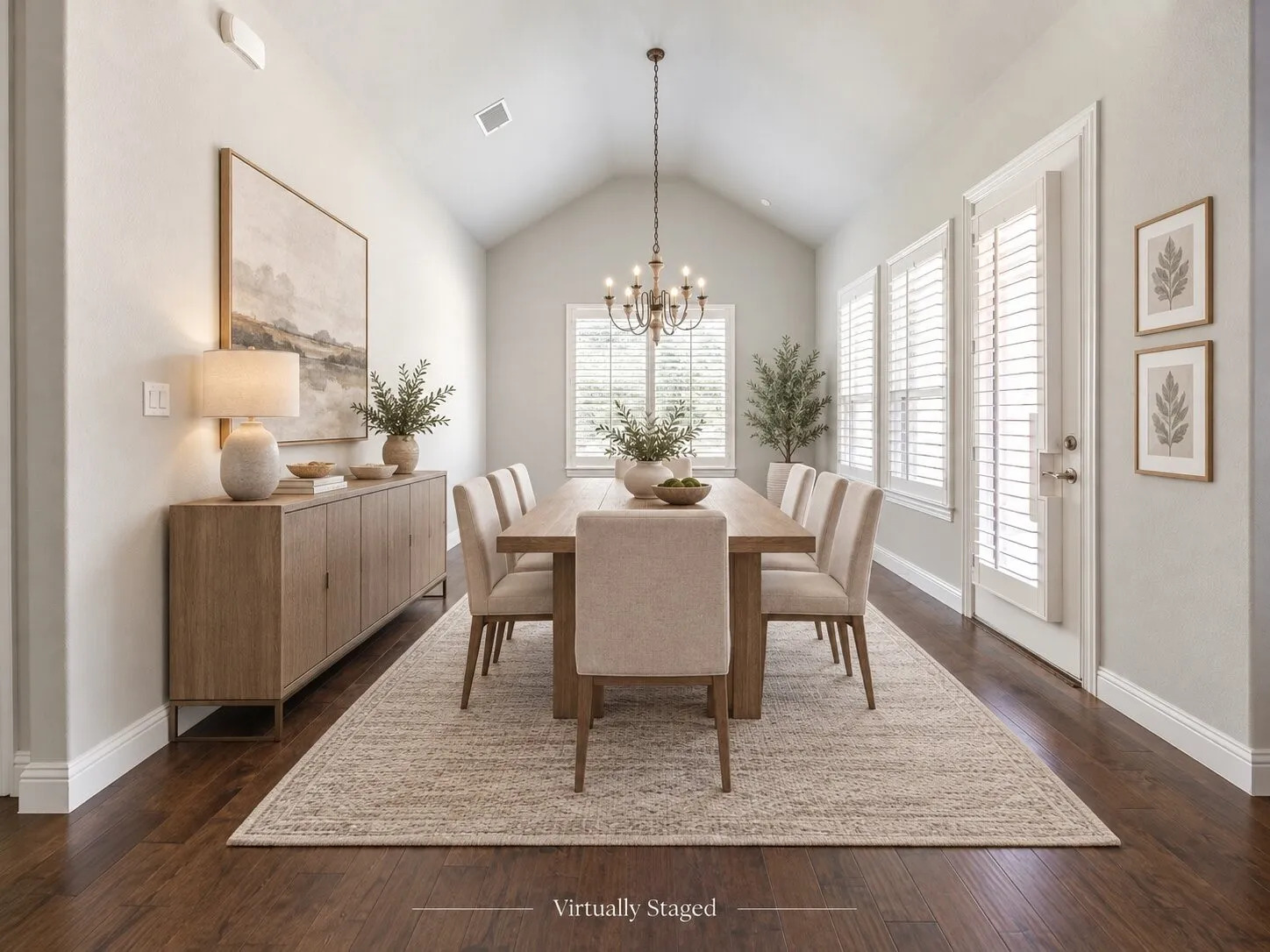 Vaulted ceiling with an elegant chandelier, rich wood-finish flooring, and multiple windows with plantation shutters