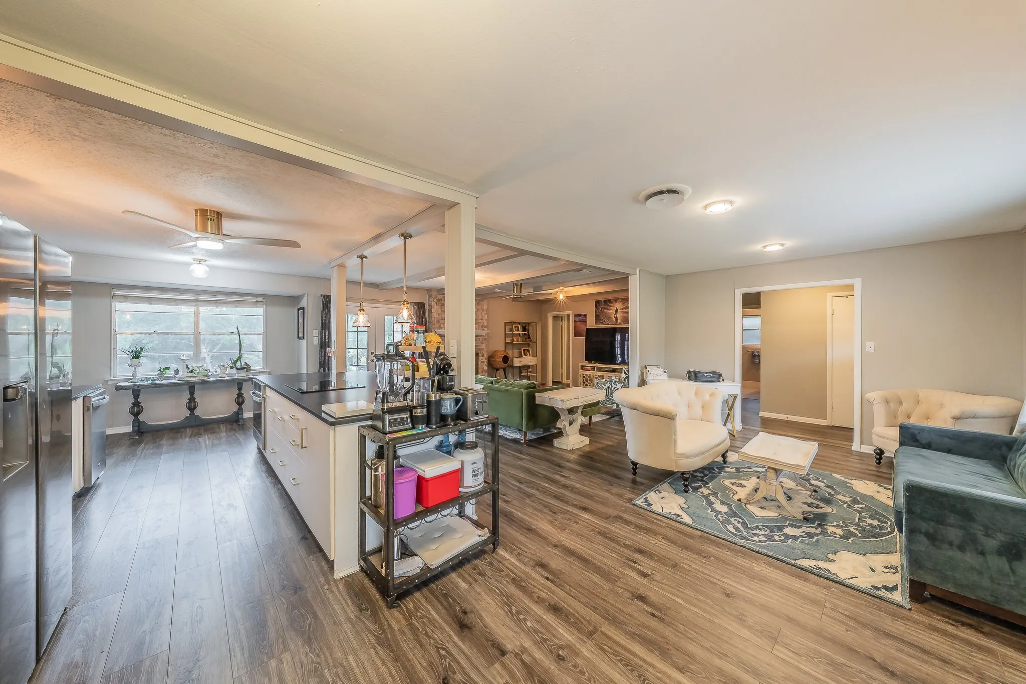 Kitchen island with dark countertop, stainless steel appliances, and wood-finish flooring