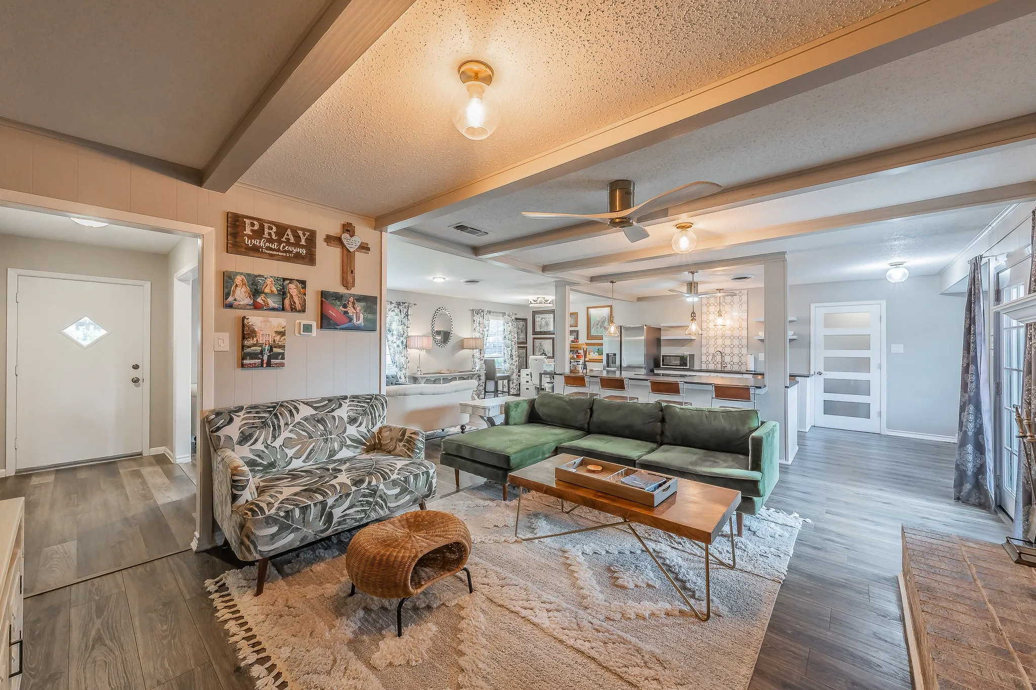 Open-concept living area featuring wood-finish flooring, exposed ceiling beams, and recessed lighting